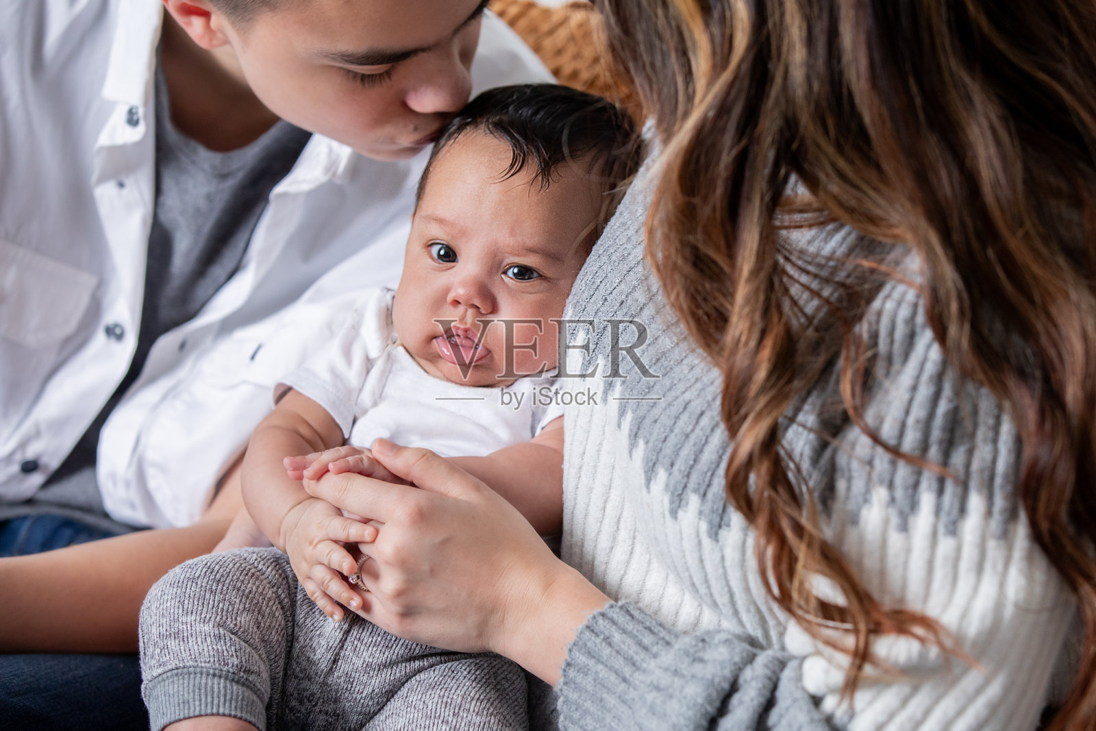 可爱的宝宝被妈妈抱着，十几岁的弟弟亲吻他的头照片摄影图片