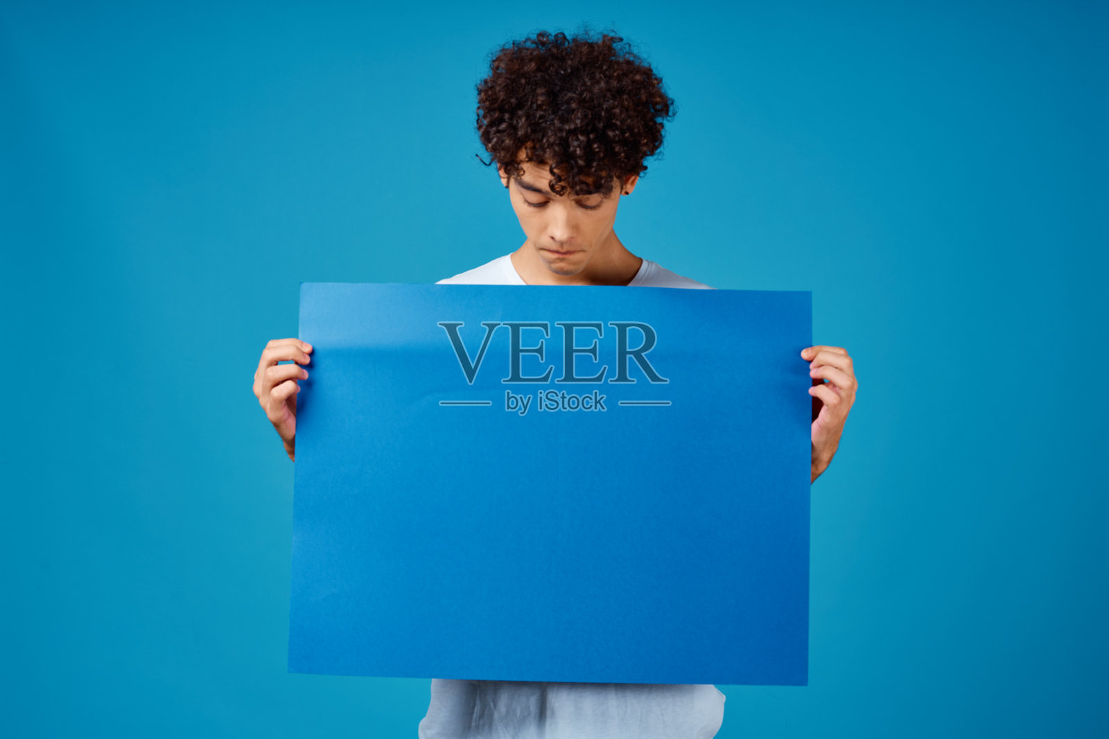 穿白t恤的人拿着一张广告模型海报照片摄影图片