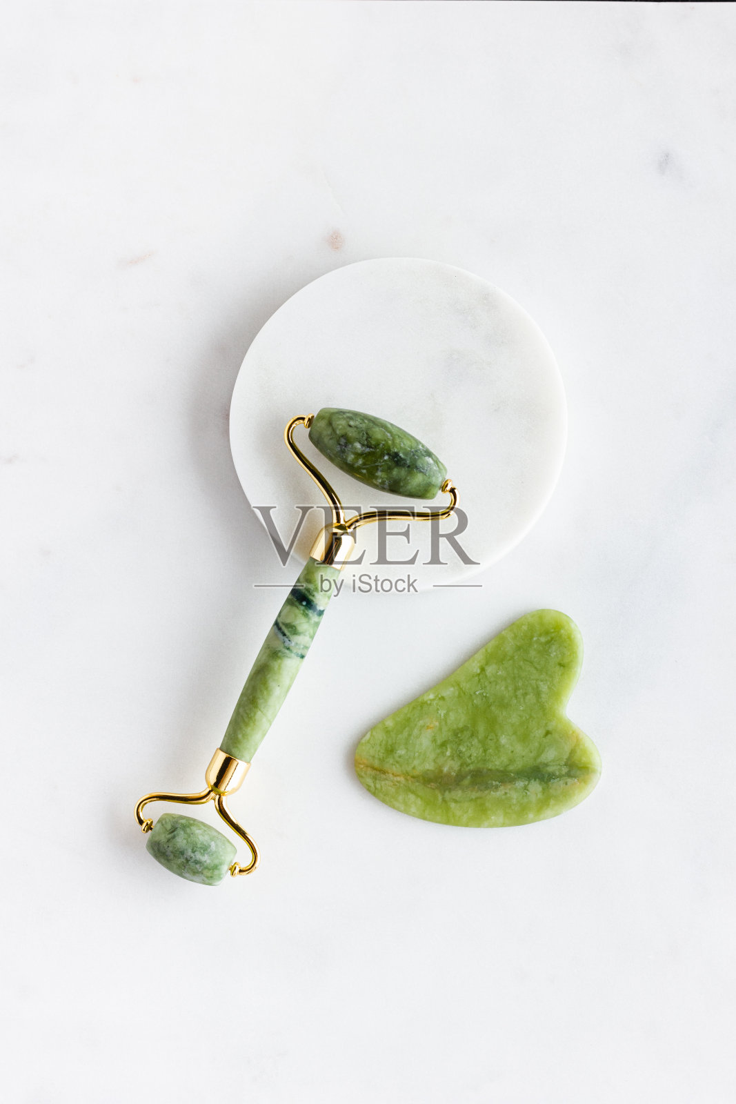 白色大理石上的青玉滚轮按摩器。照片摄影图片
