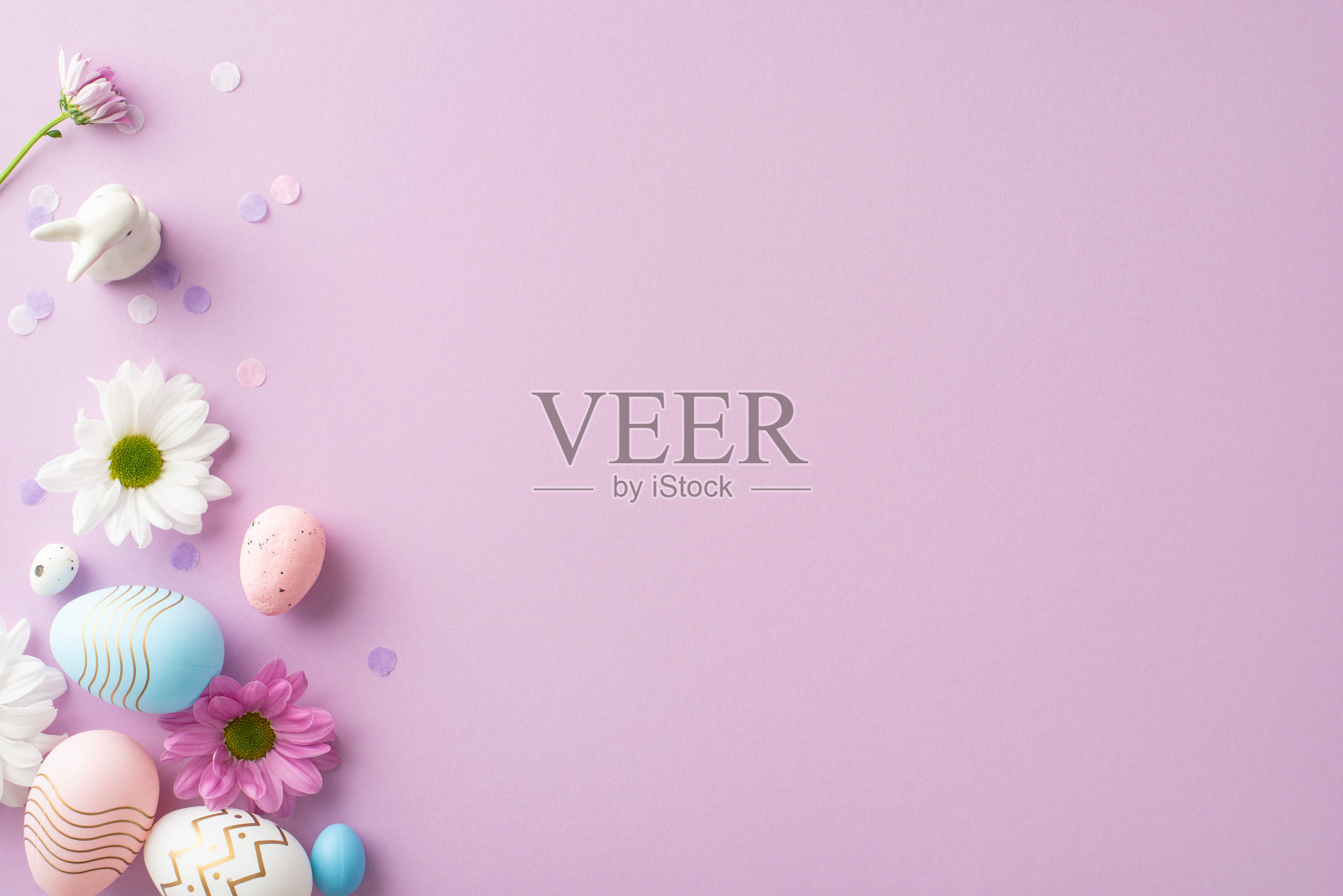 从顶视图看时尚的复活节构图，在浅紫色的背景上有鸡蛋、瓷兔、洋甘菊和五彩纸带，为个人文本或广告提供了一个地方照片摄影图片