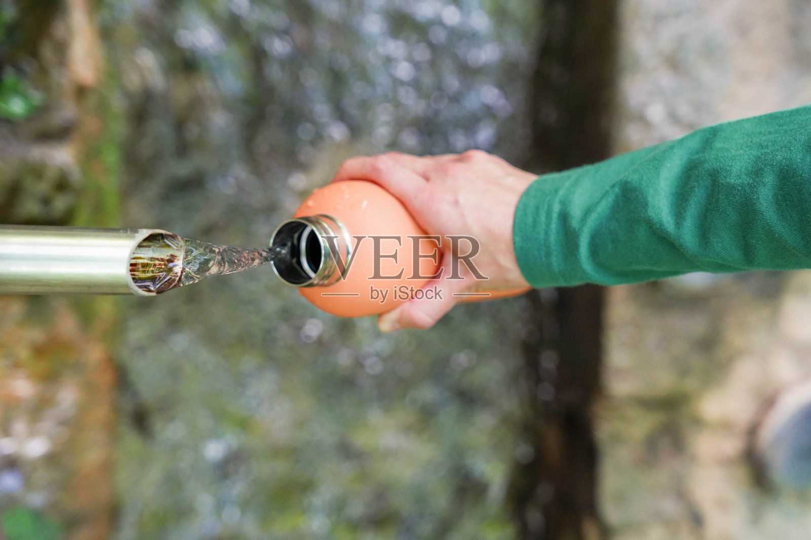 一个人正在往水瓶里倒水。这个人正在休息，在夏天补充水分。阻止干旱，拯救地球照片摄影图片