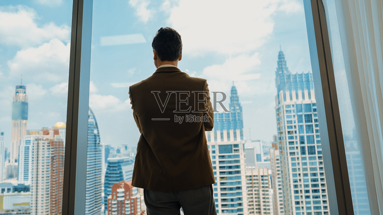 雄心勃勃的商人站在以城市景观为背景的装饰办公室里照片摄影图片
