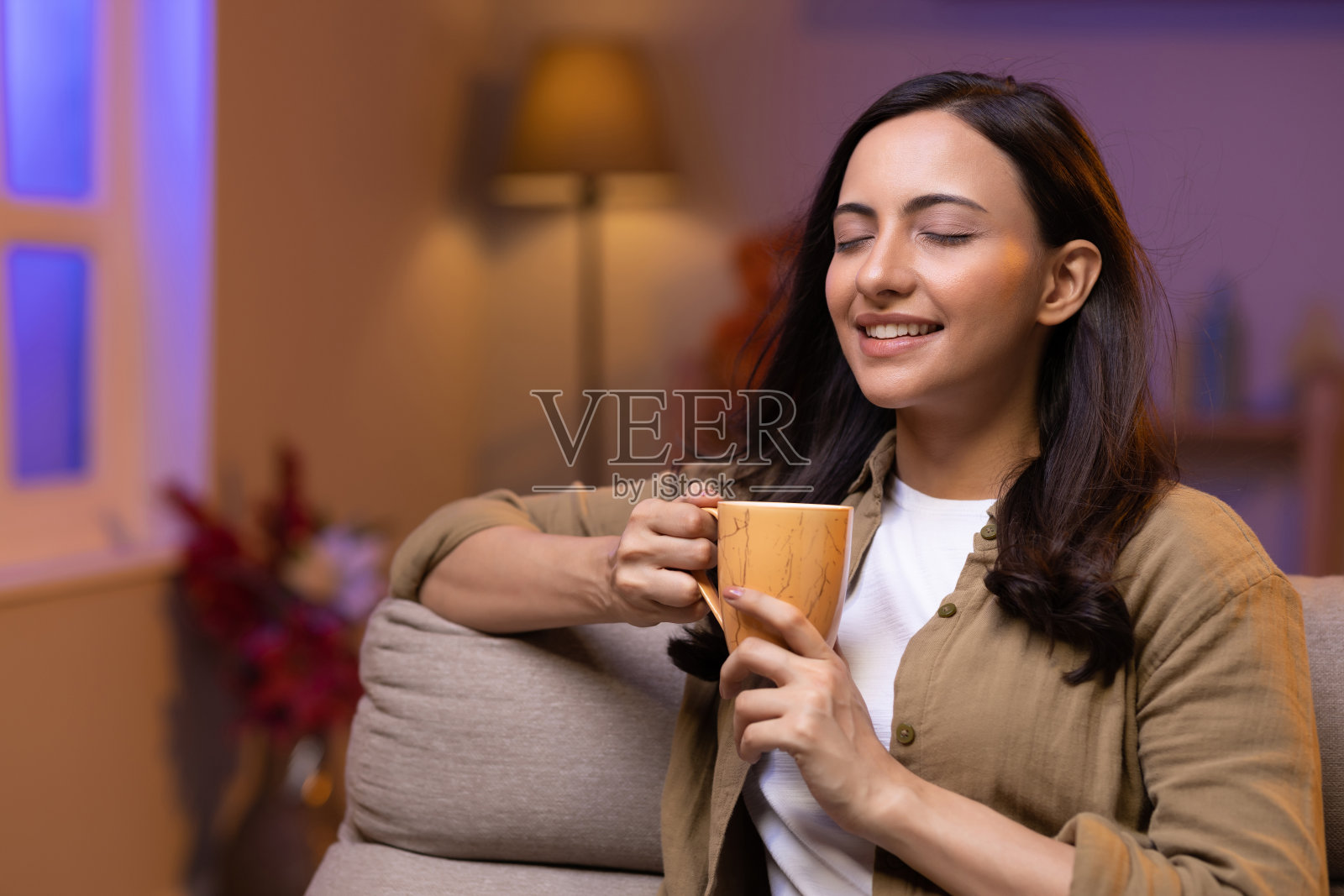 年轻女子坐在家里的沙发上喝咖啡照片摄影图片