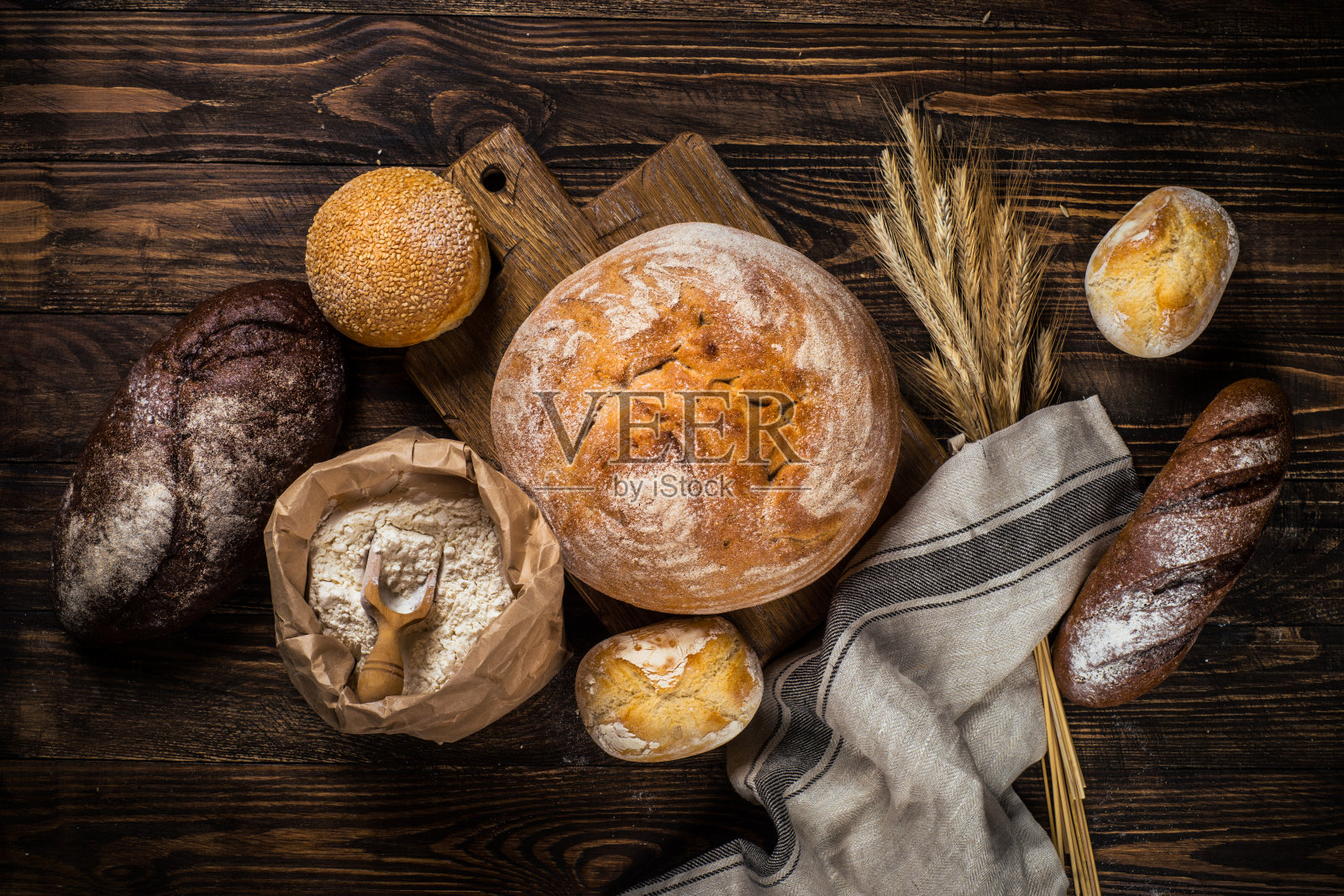 质朴的木桌上放着新鲜的面包和小圆面包。照片摄影图片