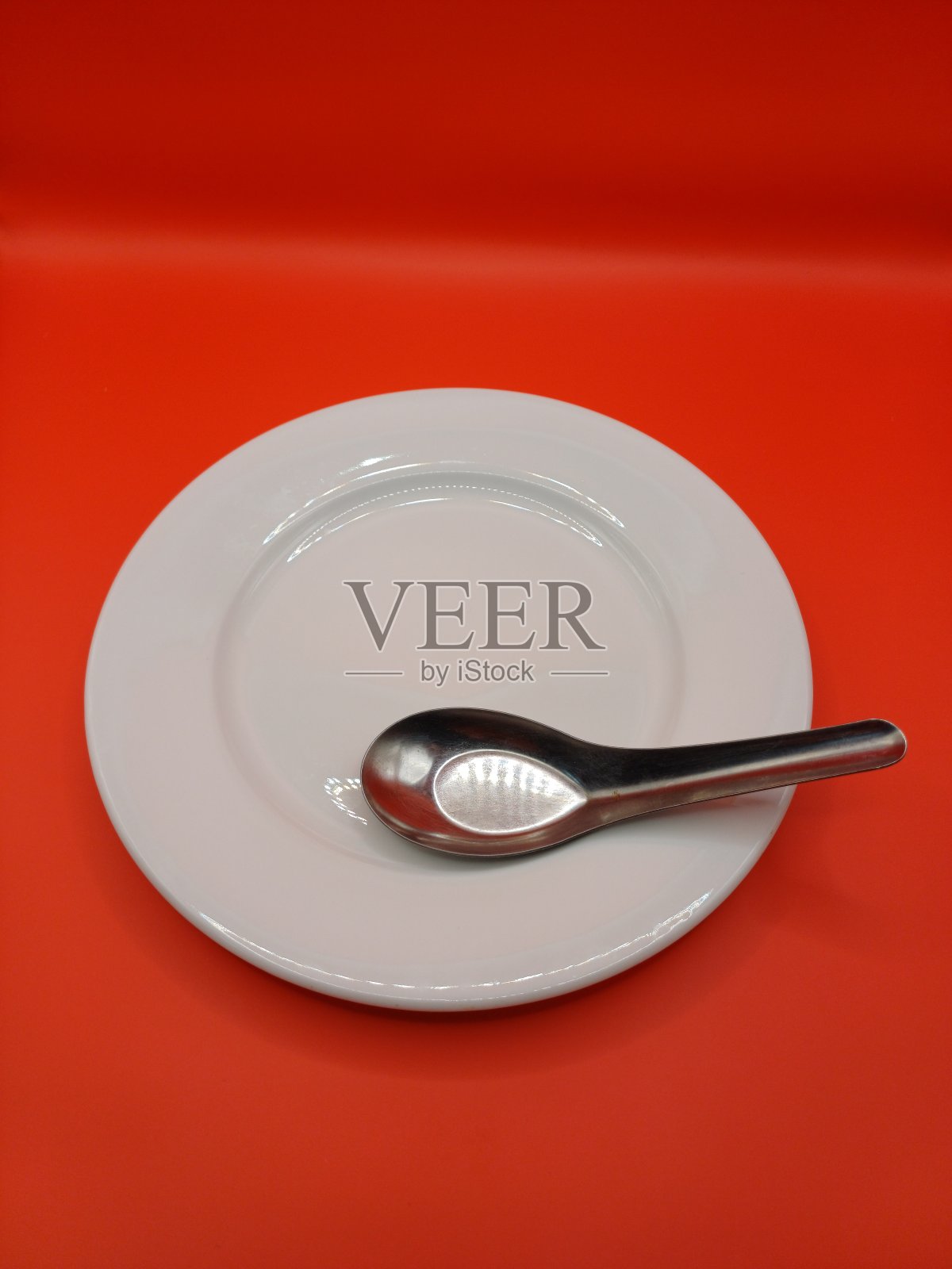 空的白色盘子和勺子在红色的背景。膳食准备概念。照片摄影图片