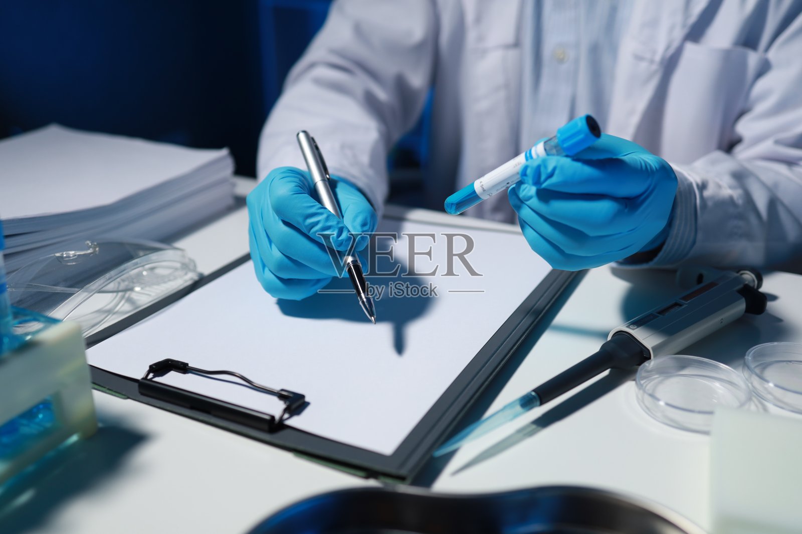 一位研究人员正在做笔记。一个生物化学科学家正在为他的老板写一份关于他一天工作的报告。照片摄影图片