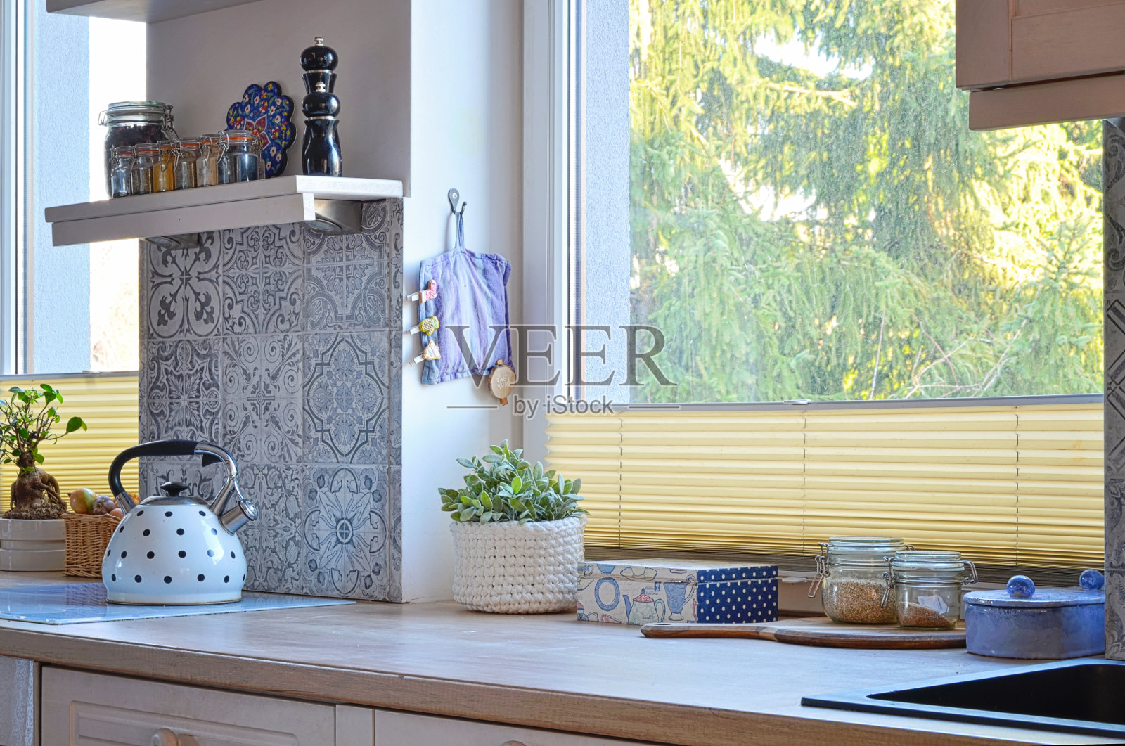 厨房可透过窗户看到绿色和木制台面，配有烤箱和水壶。家庭内部。照片摄影图片