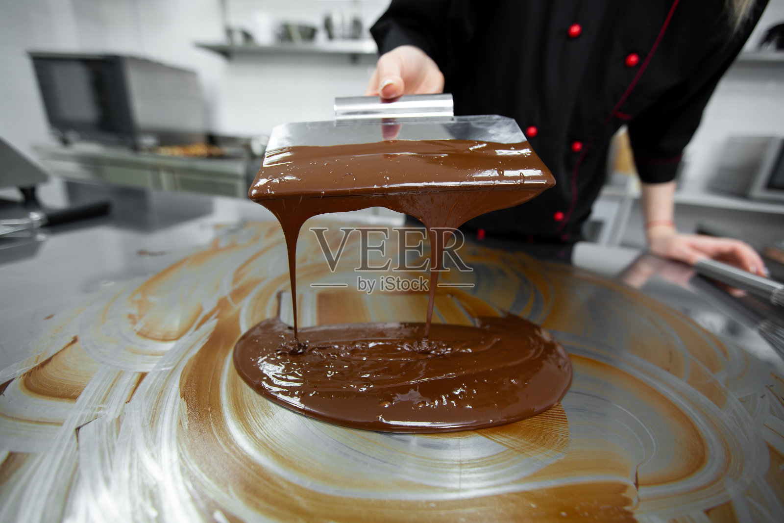 糕点师用锅铲回火融化巧克力的特写。照片摄影图片