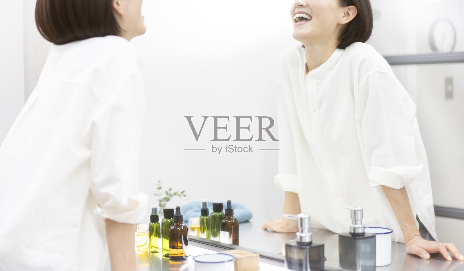 一个女人对着镜子里的自己微笑。照片摄影图片