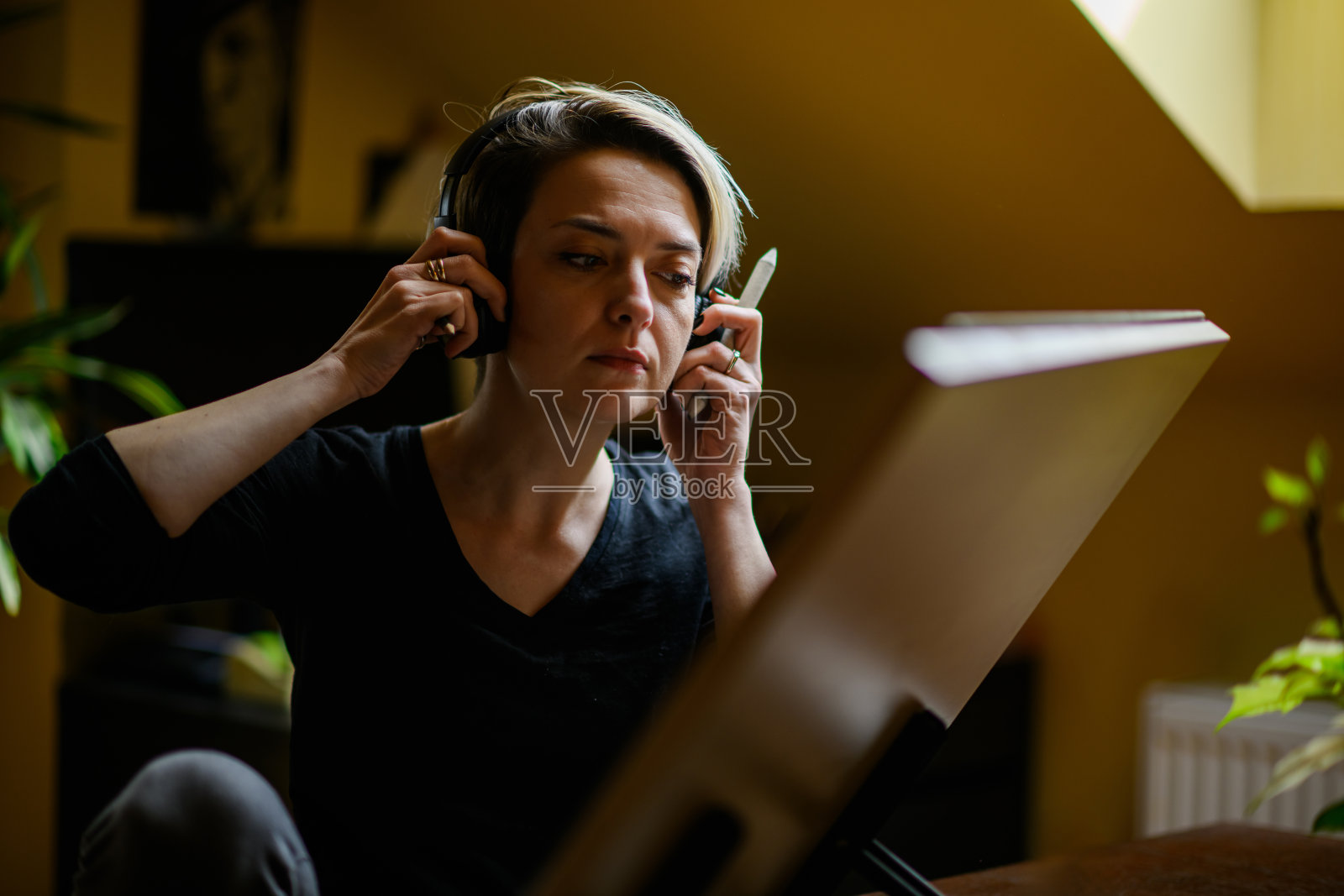 一位艺术家戴着耳机看她的作品的肖像。照片摄影图片