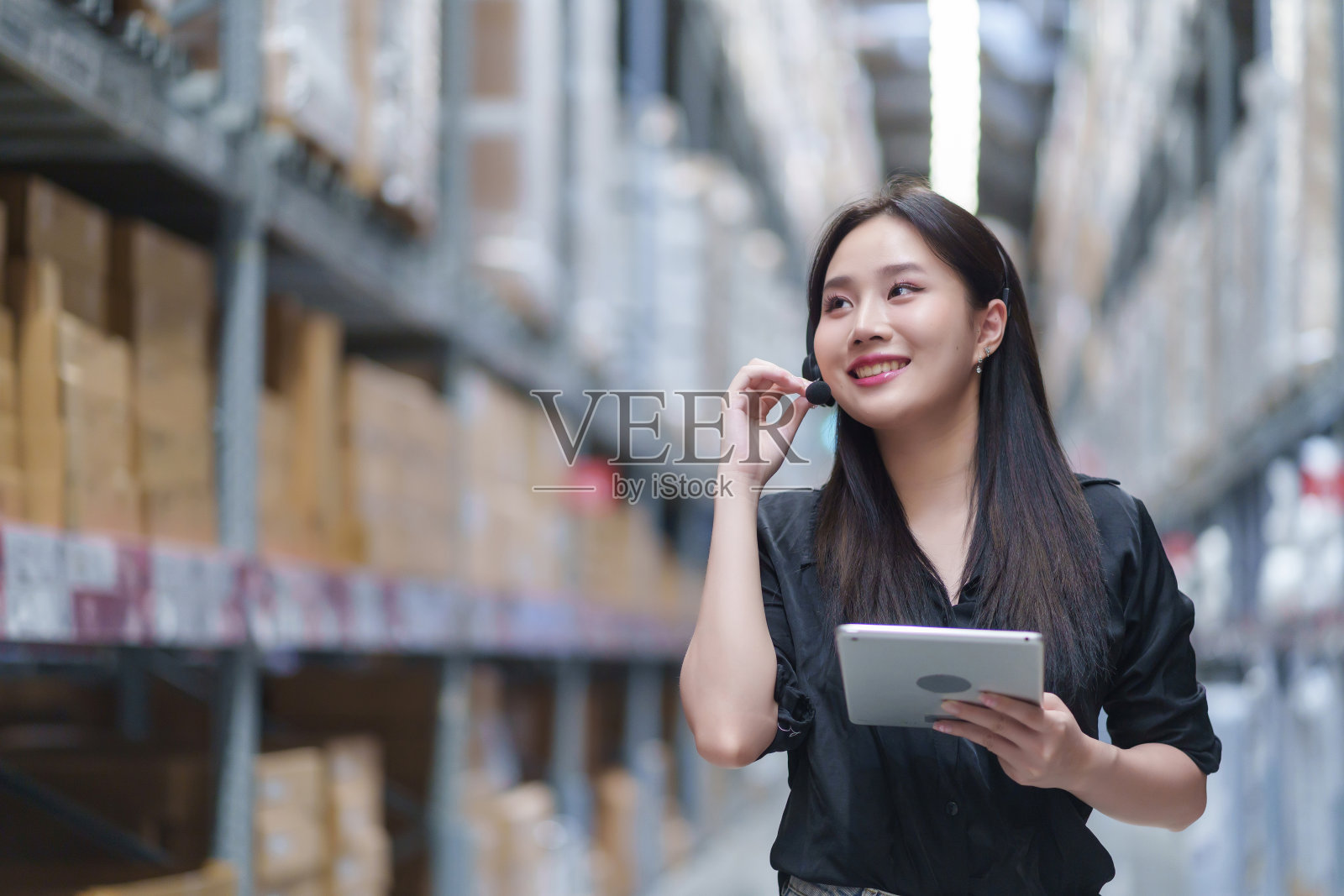 女性库存经理检查仓库库存并与客户交谈信息。他们检查产品库存。在后台库存的包裹与产品准备发货。照片摄影图片