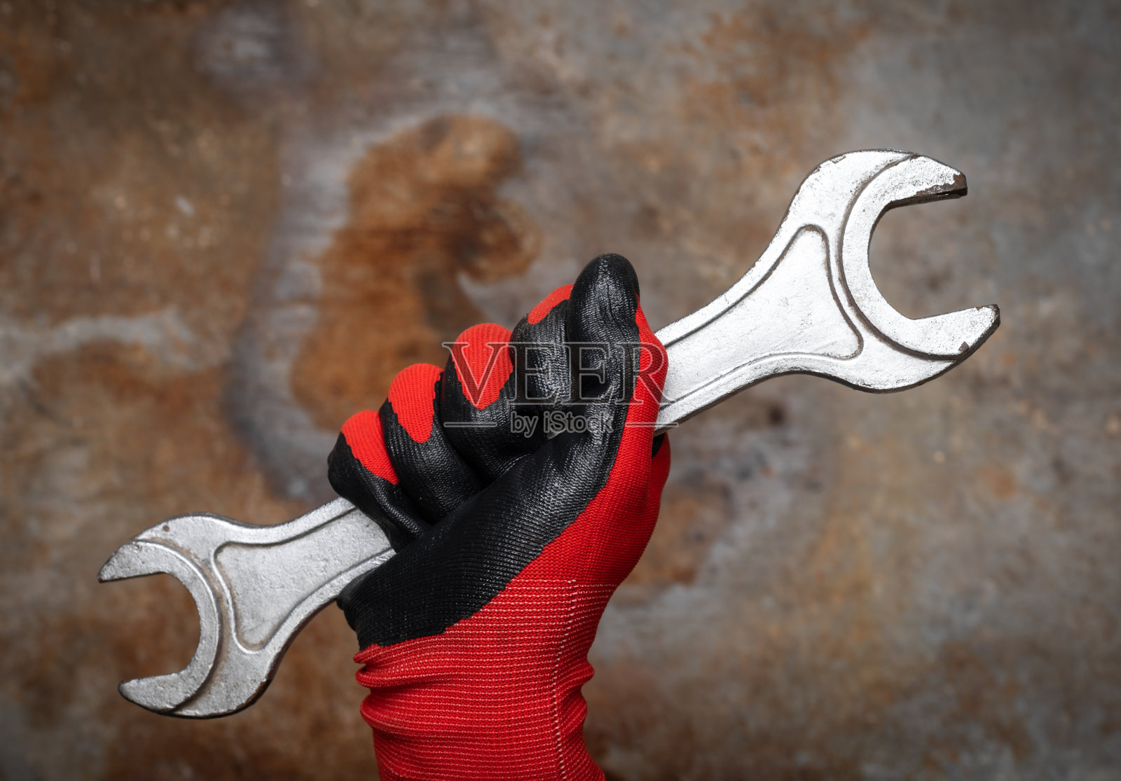 戴着手套的手握扳手在生锈的背景照片摄影图片