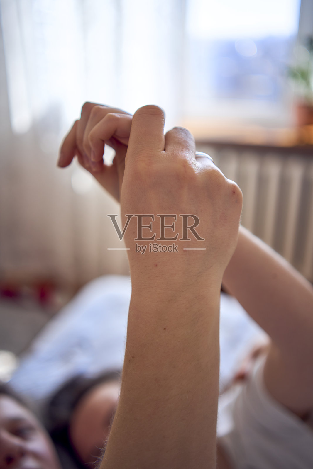 年轻的夫妇在床上手牵着手，一个女孩在一个男孩的肩膀上，温柔的拥抱和触摸照片摄影图片