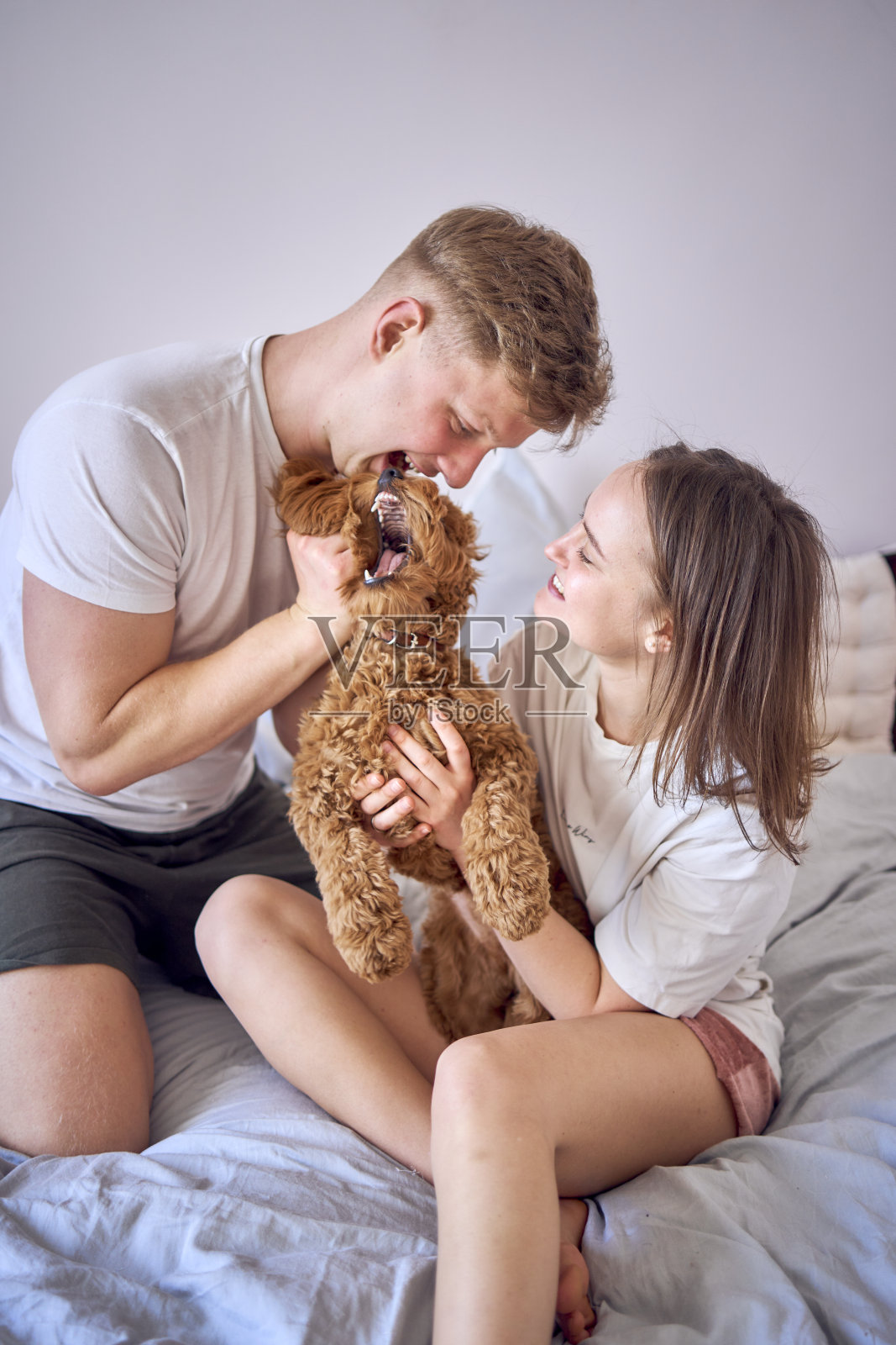 一对夫妇在床上和一个小女孩玩耍，极简主义照片摄影图片
