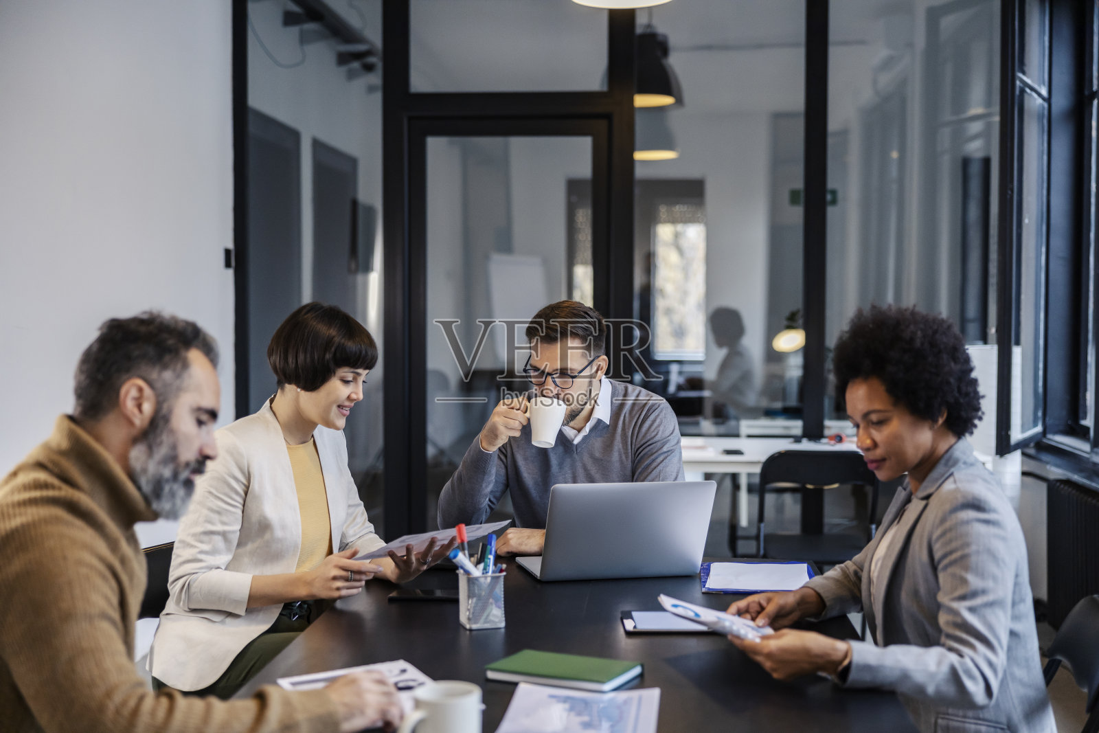 不同文化背景的同事坐在会议室做简报。照片摄影图片