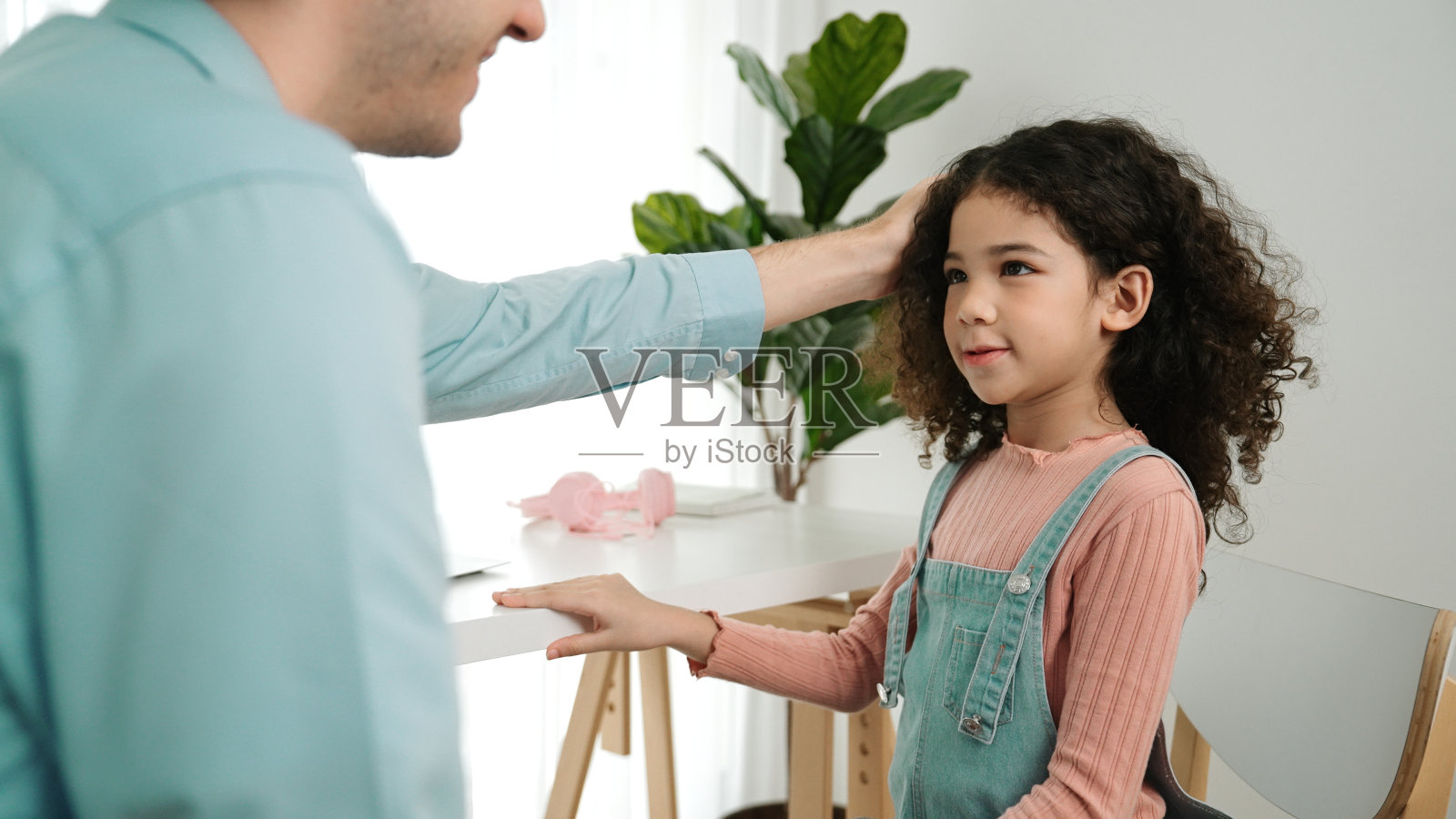 在笔记本电脑屏幕显示提示时，积极的父亲与女儿交谈。教育学。照片摄影图片