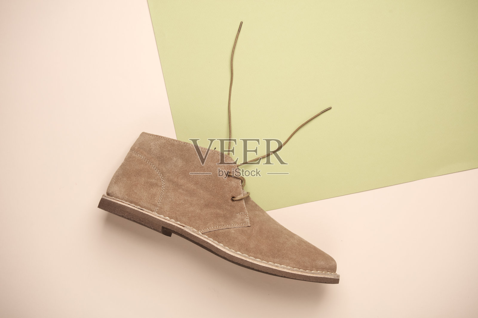 米绿色背景的麂皮沙漠靴。俯视图照片摄影图片