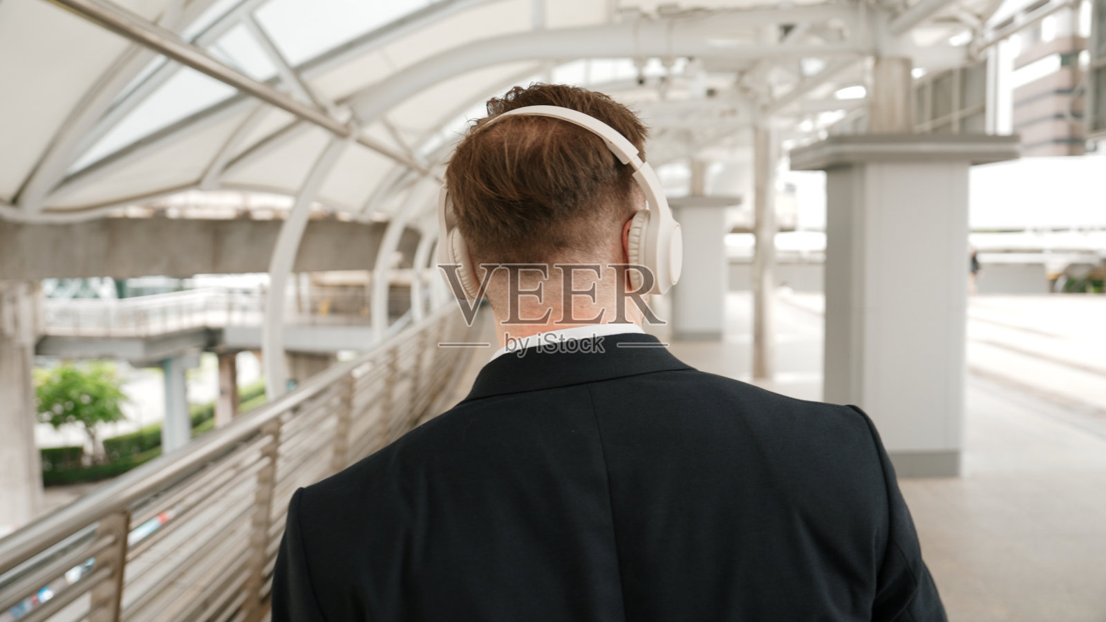 快乐的商人在桥牌上戴着耳机跳舞。后视图。彬彬有礼的。照片摄影图片