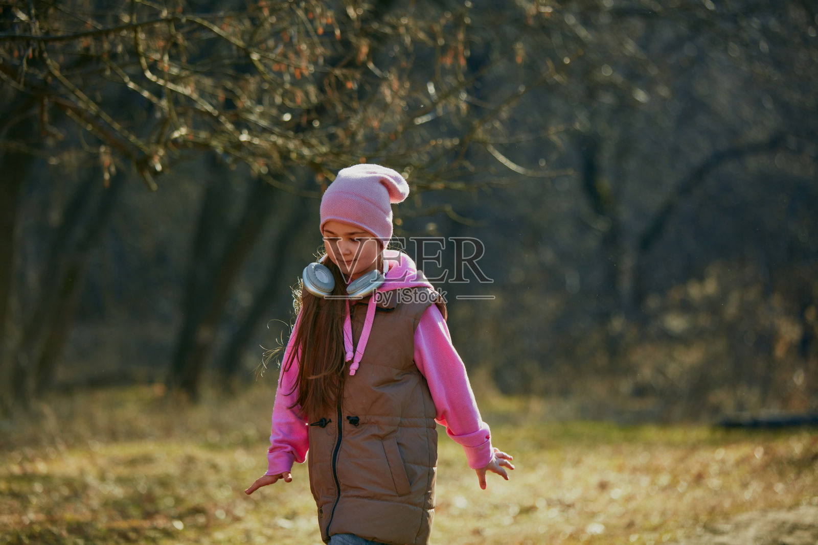 微笑的孩子，戴着耳机，背着背包，在金色的阳光下跋涉。环境课。儿童发展的户外活动。照片摄影图片