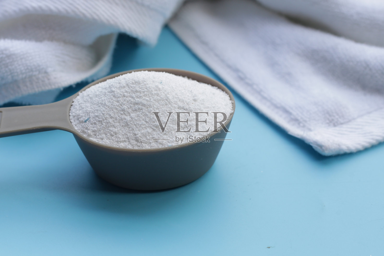 用毛巾将洗衣粉放入量匙中。衣服的概念。照片摄影图片