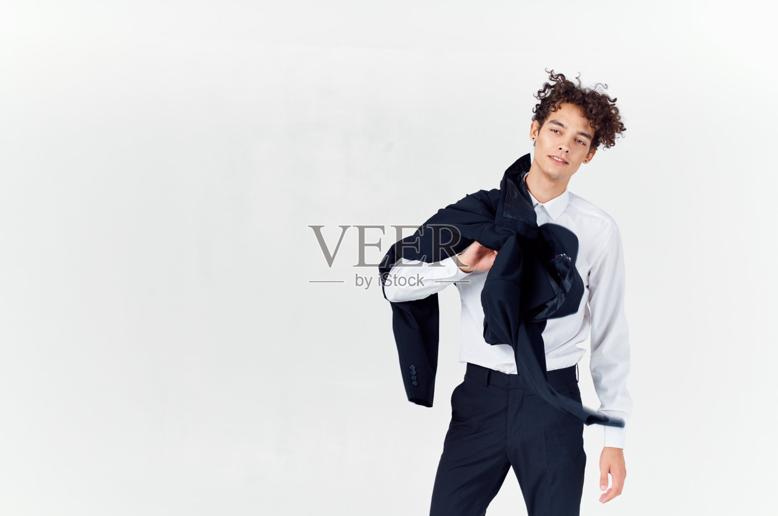 一个卷头发，穿着经典西装的男人，手里拿着一件时尚风格的夹克照片摄影图片