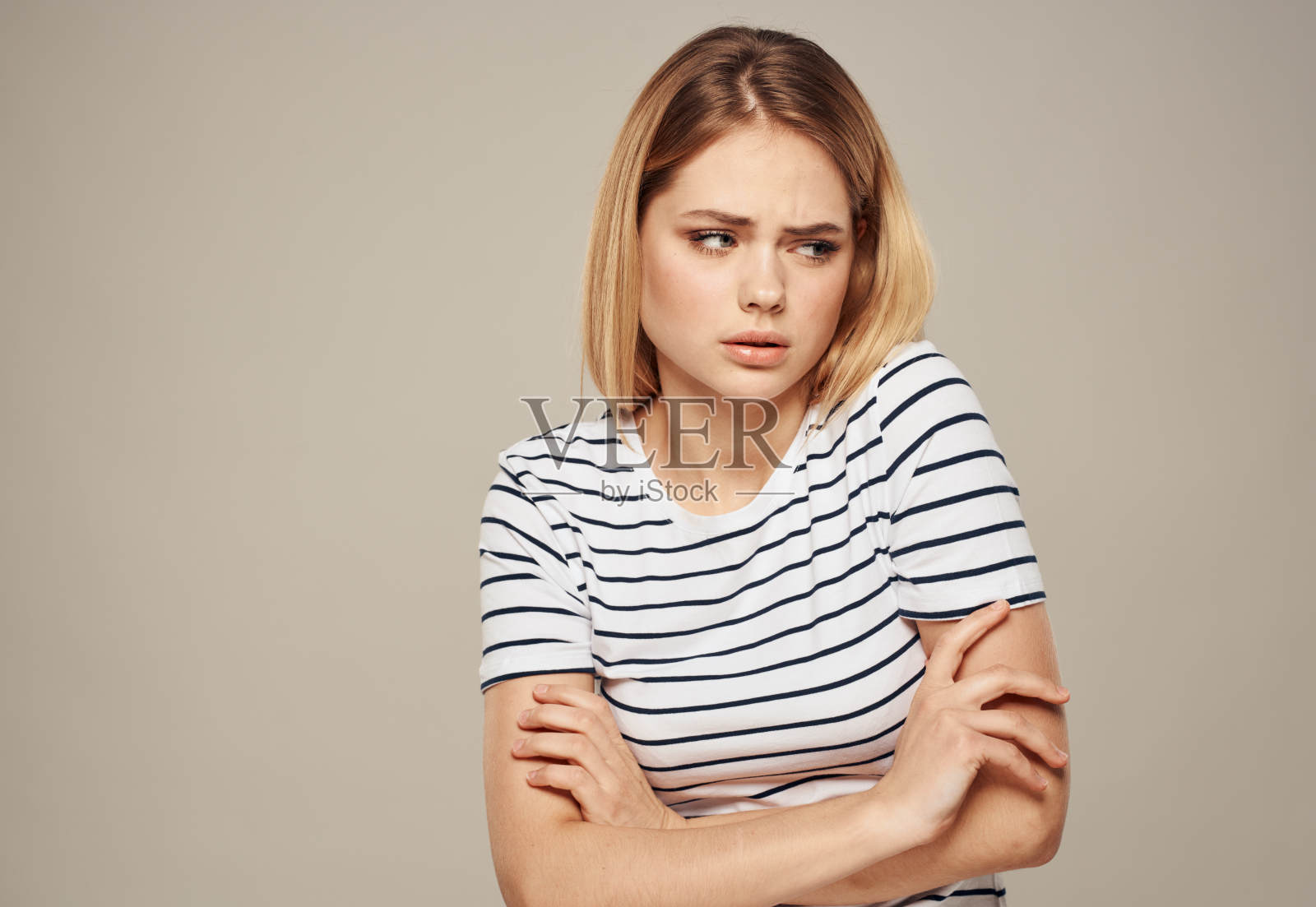 一名身穿t恤的女子被冒犯了，她将双臂交叉放在胸前，背景是米色照片摄影图片
