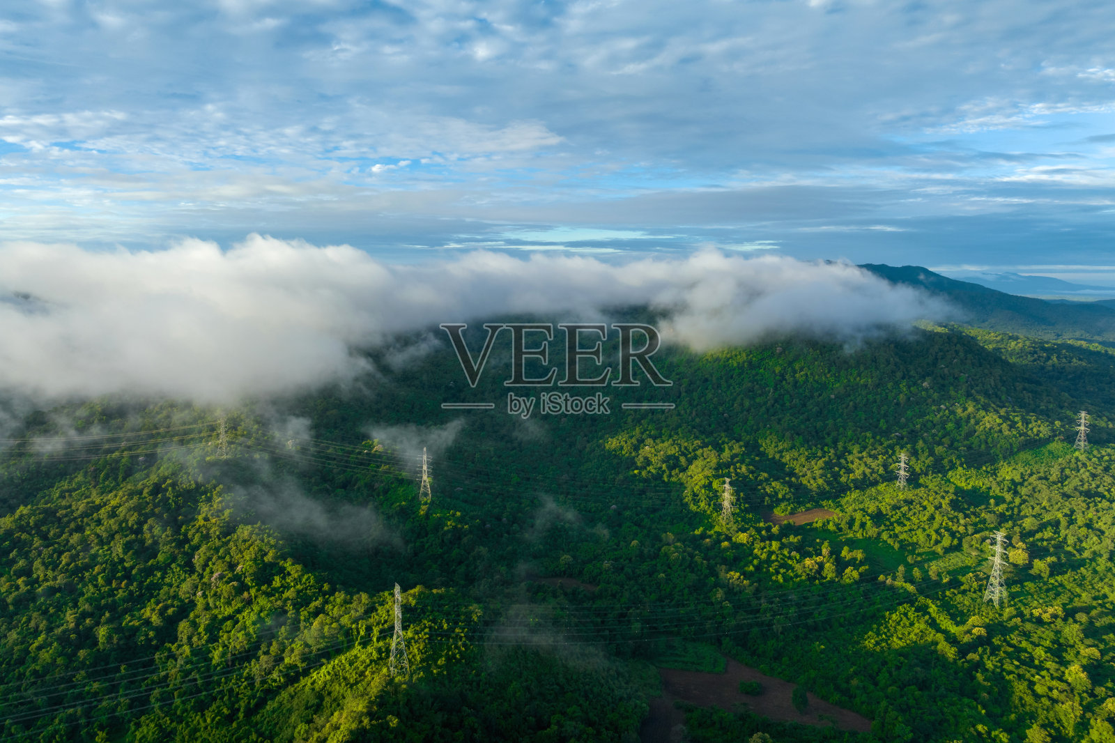 晨雾笼罩着山脉上的高压输电塔。照片摄影图片