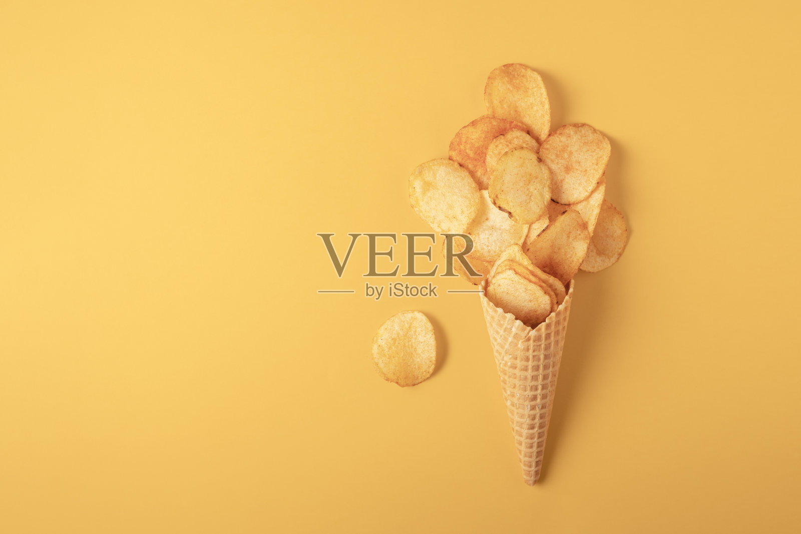 黄色背景的华夫蛋筒里的脆薯片，俯视图照片摄影图片