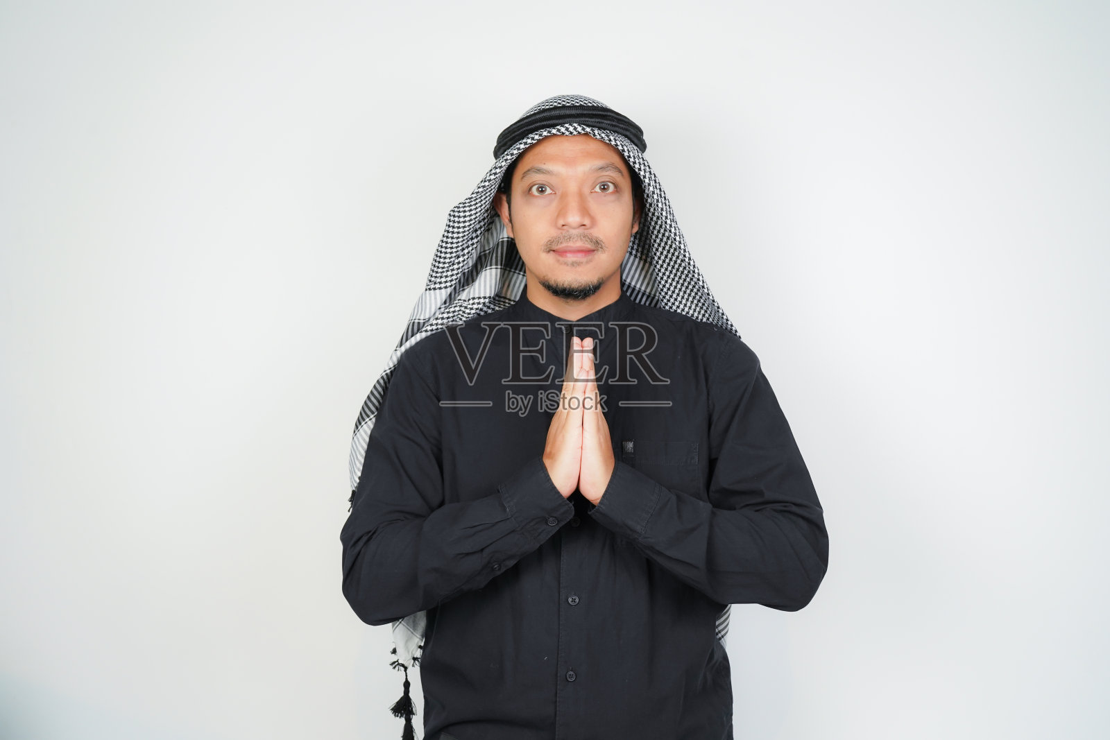 快乐微笑的亚洲穆斯林男子，戴着阿拉伯头巾，站着开斋节的问候手势，欢迎斋月孤立照片摄影图片