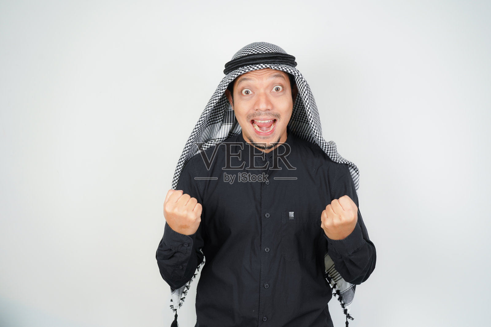 亚洲穆斯林男子充满热情和自信地庆祝，戴着阿拉伯头巾，站着，握紧拳头孤立照片摄影图片