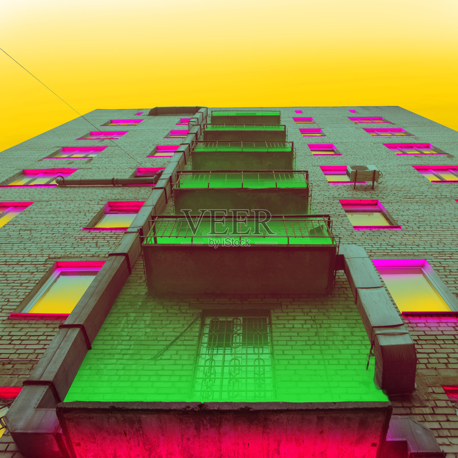 海报，当代艺术拼贴。高大的砖砌建筑，绿色和粉红色的霓虹灯照亮了窗户和阳台。城市街头风格。照片摄影图片