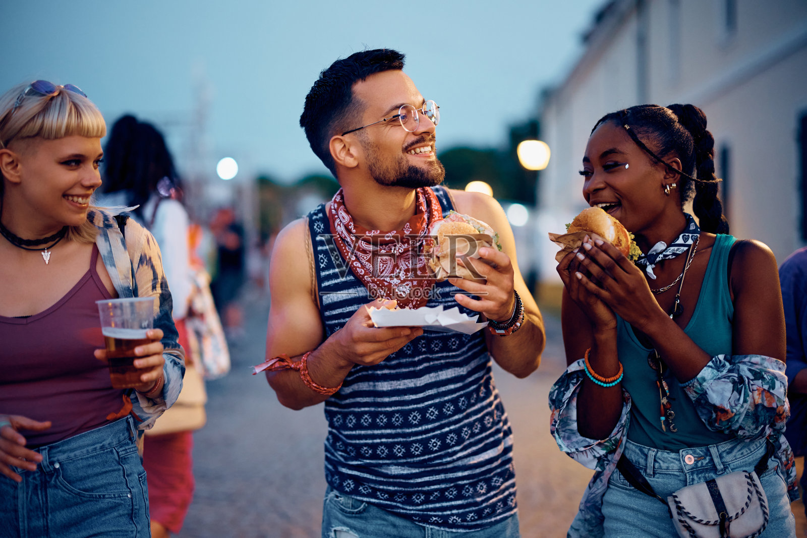 快乐的节日去吃汉堡和朋友在夏天的晚上玩。照片摄影图片