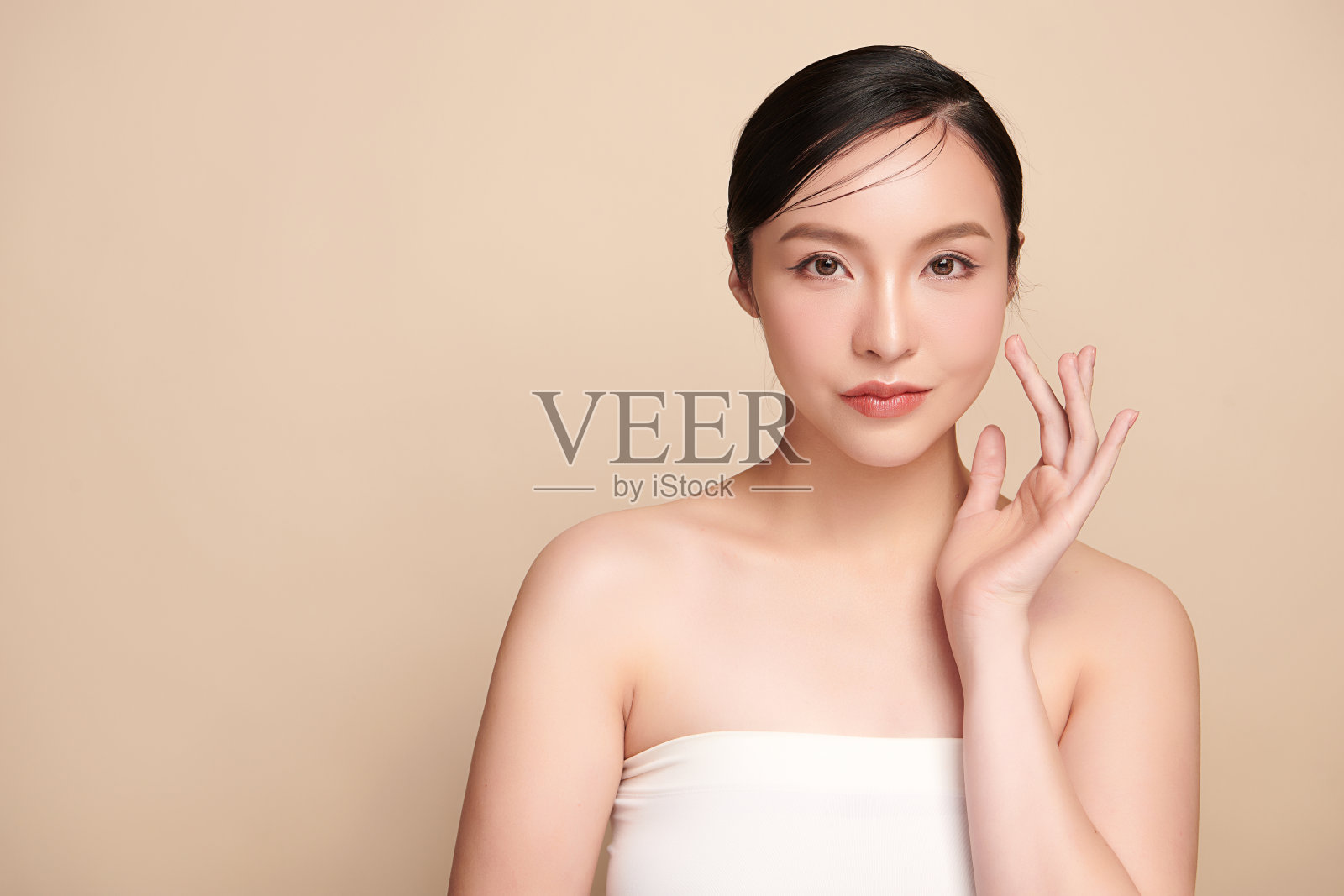 美丽的年轻亚洲女性干净新鲜的皮肤在米色背景，面部护理，面部护理，美容，美容和水疗，亚洲女性肖像。照片摄影图片