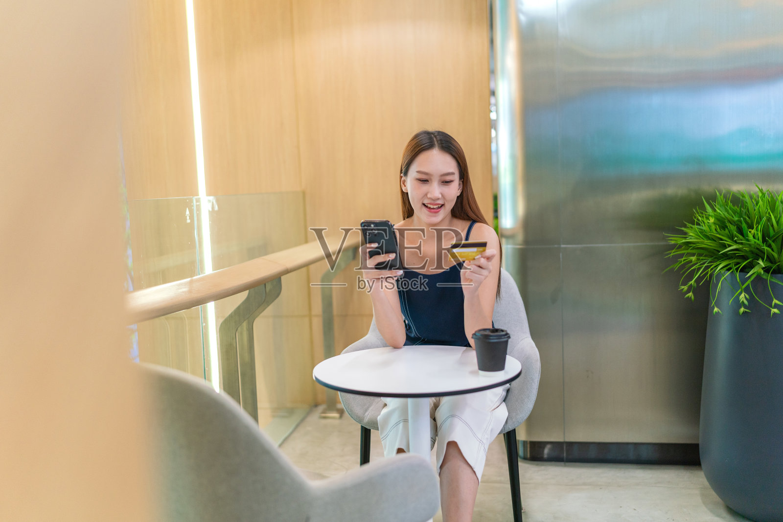 年轻的亚洲女性在咖啡厅用智能手机进行数字银行信用卡交易照片摄影图片