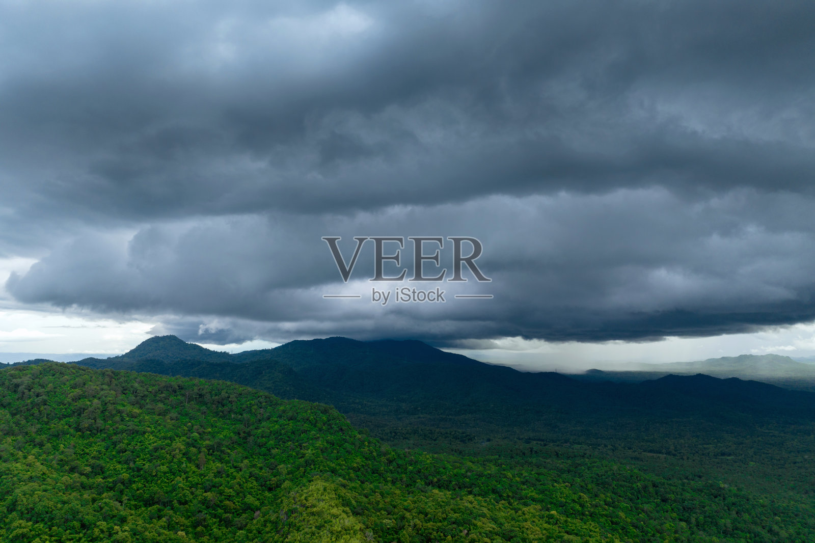 巨大的黑色雨云和暴雨落在山区的森林地区。照片摄影图片