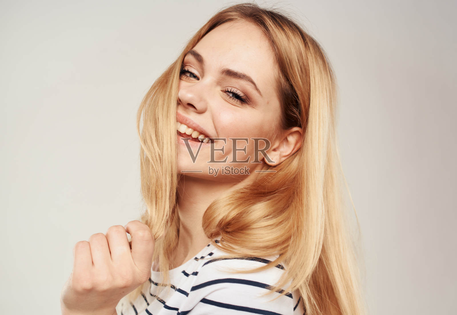 身穿条纹t恤的金发女子在米色背景上的特写镜头照片摄影图片