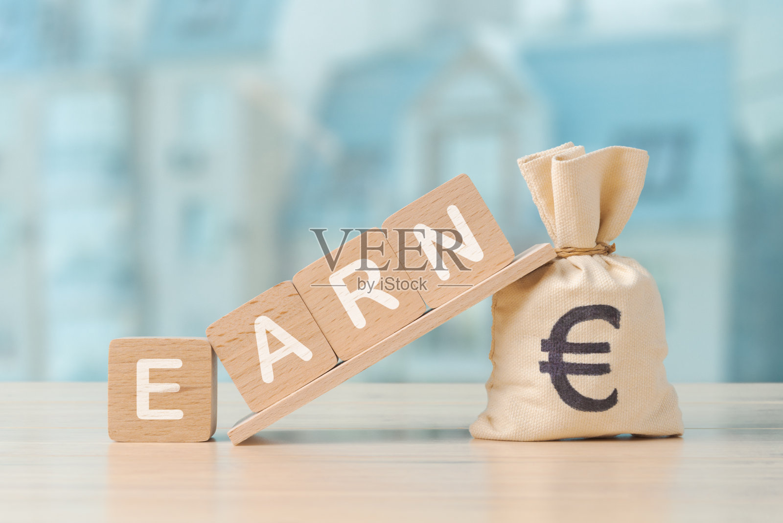 图片展示了一个钱袋与欧元符号和木块拼写挣，挣钱的概念照片摄影图片