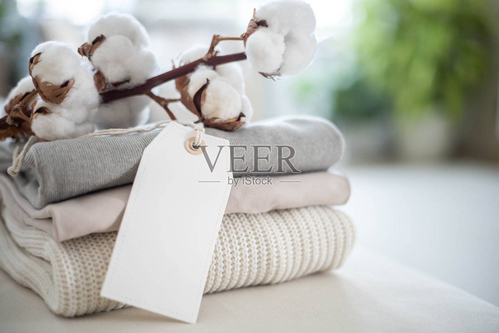 一堆干净的中性色针织衫。概念销售，回收和储存的服装。空白的白色标签。照片摄影图片