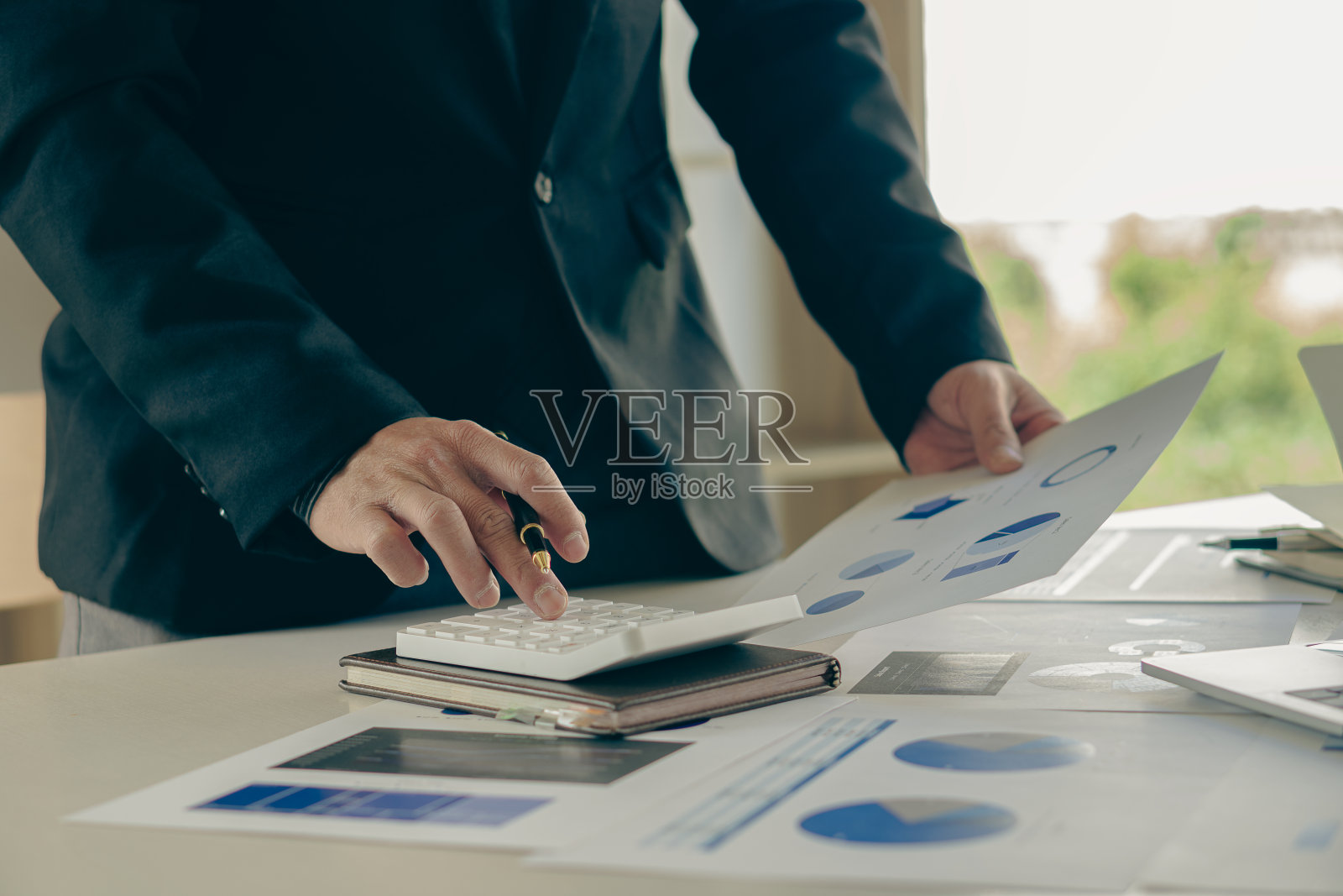 年轻的亚洲男性商人正在按计算器计算收入、税收和支出、支付信用卡账单或发薪日。特写照片照片摄影图片