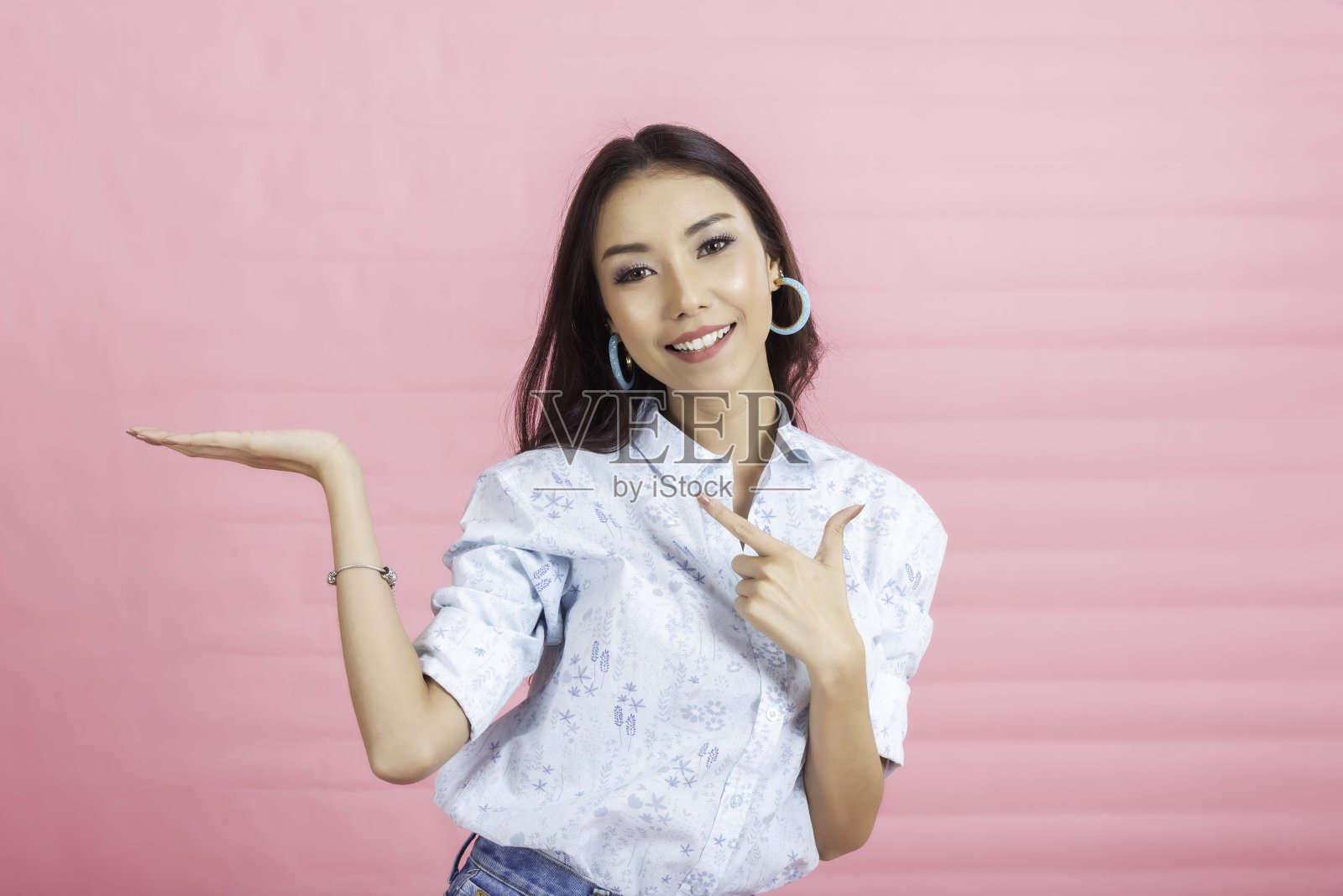 快乐的年轻女子视图采取工作室粉红色的背景。照片摄影图片