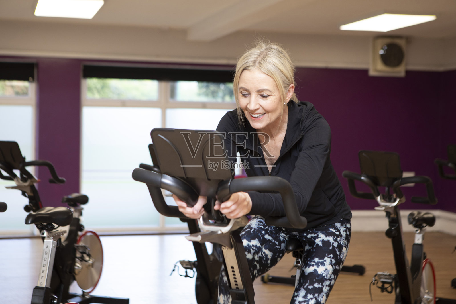 在健身房里骑健身自行车的妇女照片摄影图片