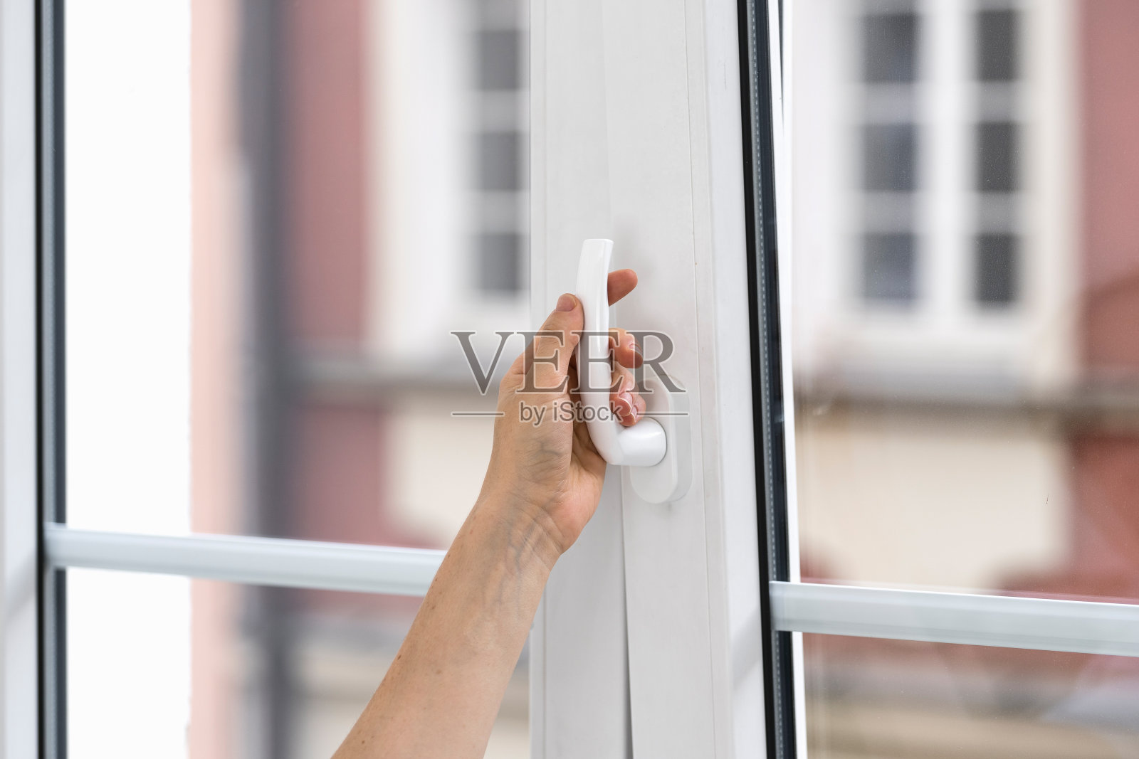 选择性地关注女性在公寓里转动手柄和打开窗户的手。照片摄影图片