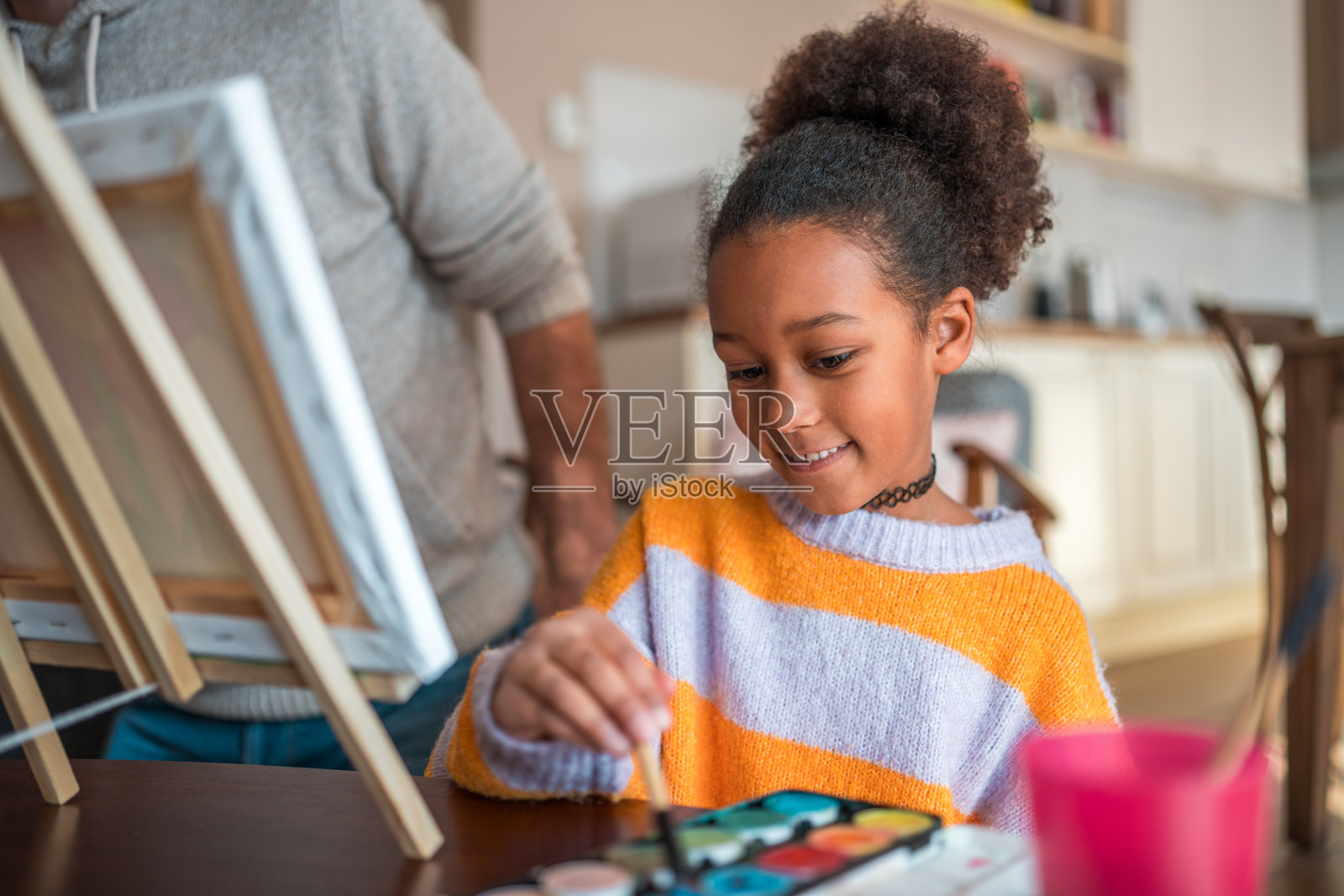 混血小女孩在大人的监督下在家画画照片摄影图片