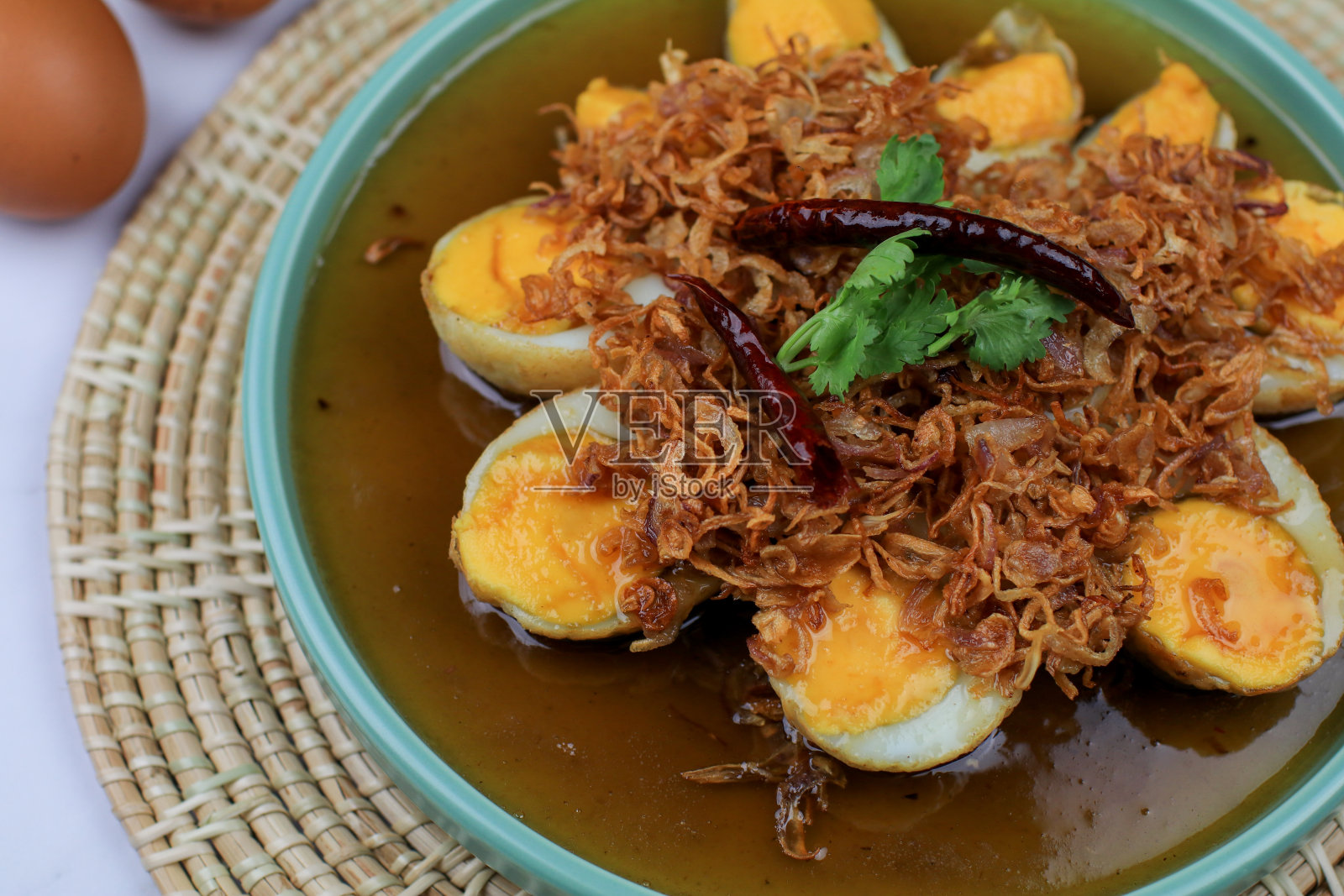 罗望子酱煎煮蛋，上面撒上炒蒜、红洋葱和香菜。泰国菜。自制的食物。照片摄影图片