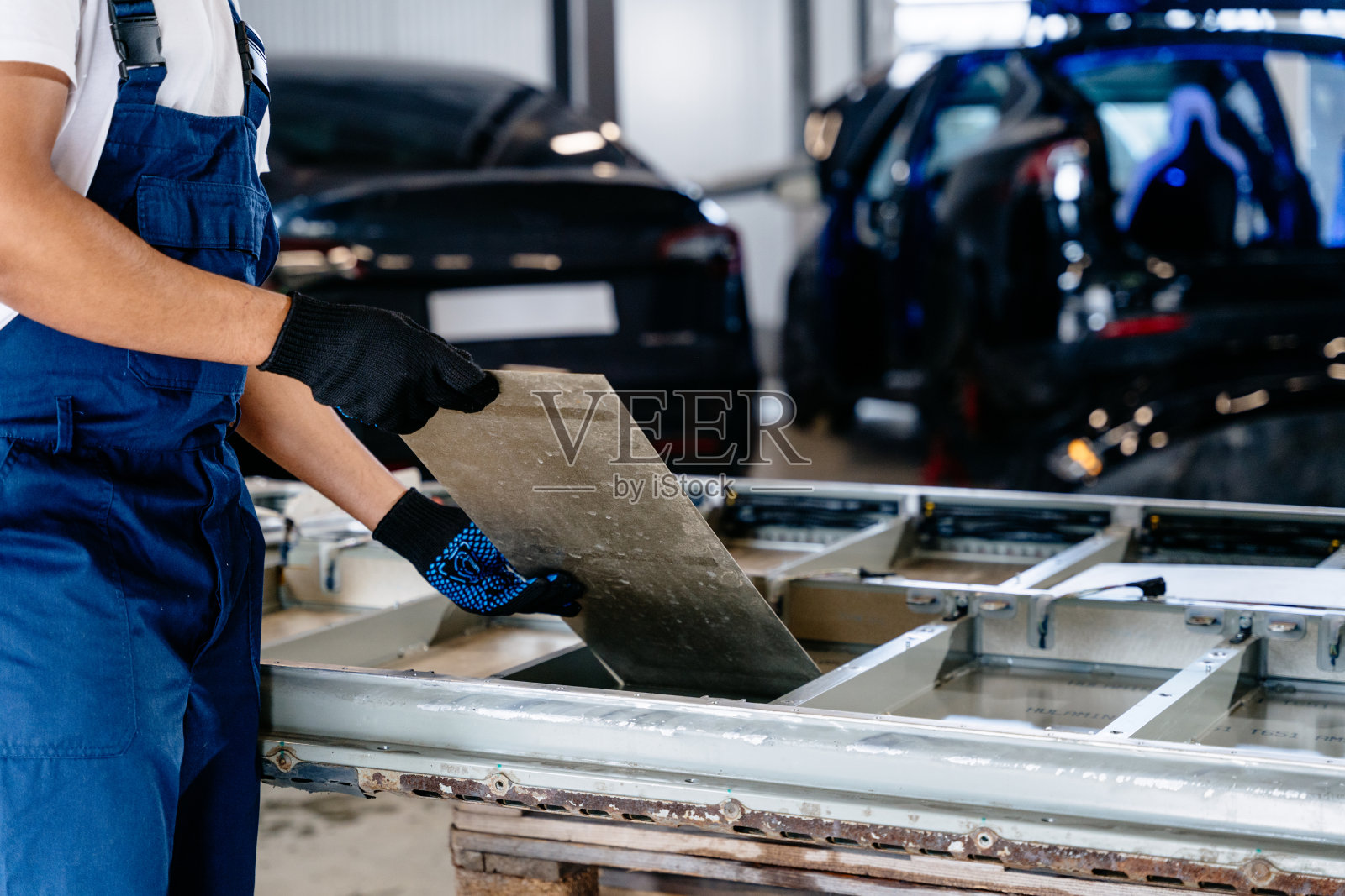 男性机械工程师，在车间从事汽车电池模块工作。平台上的空电池组模块从车上卸下进行维修。照片摄影图片