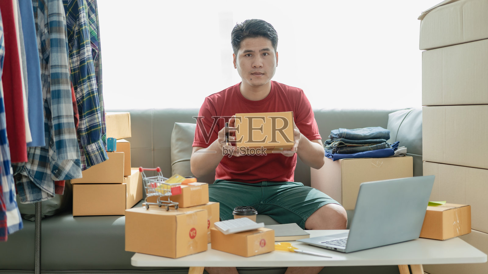 网店老板在网上检查网站上的订单，与客户确认订单，并将产品包装在包裹箱中发货。中小企业概念网上销售产品照片摄影图片