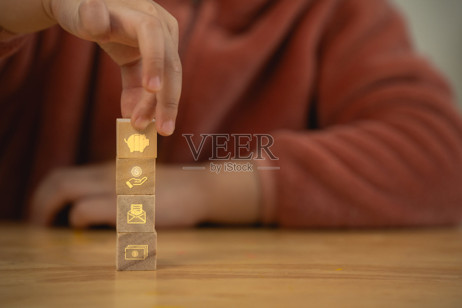 一个人拿着一堆木块，上面有一个关于省钱计划的金色虚拟图标。各区块在理财理财理念上有着不同的符号。照片摄影图片