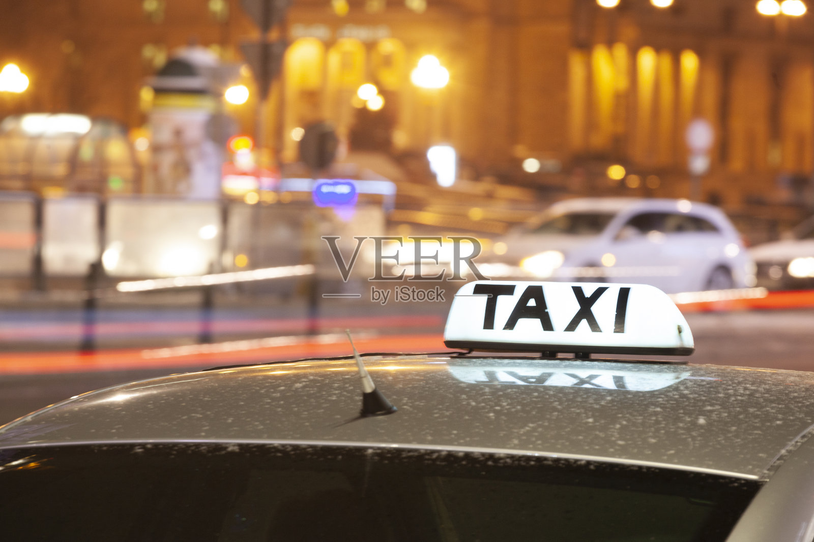 在大城市的夜间街道上，闪闪发光的出租车铭文紧挨着过往的汽车照片摄影图片