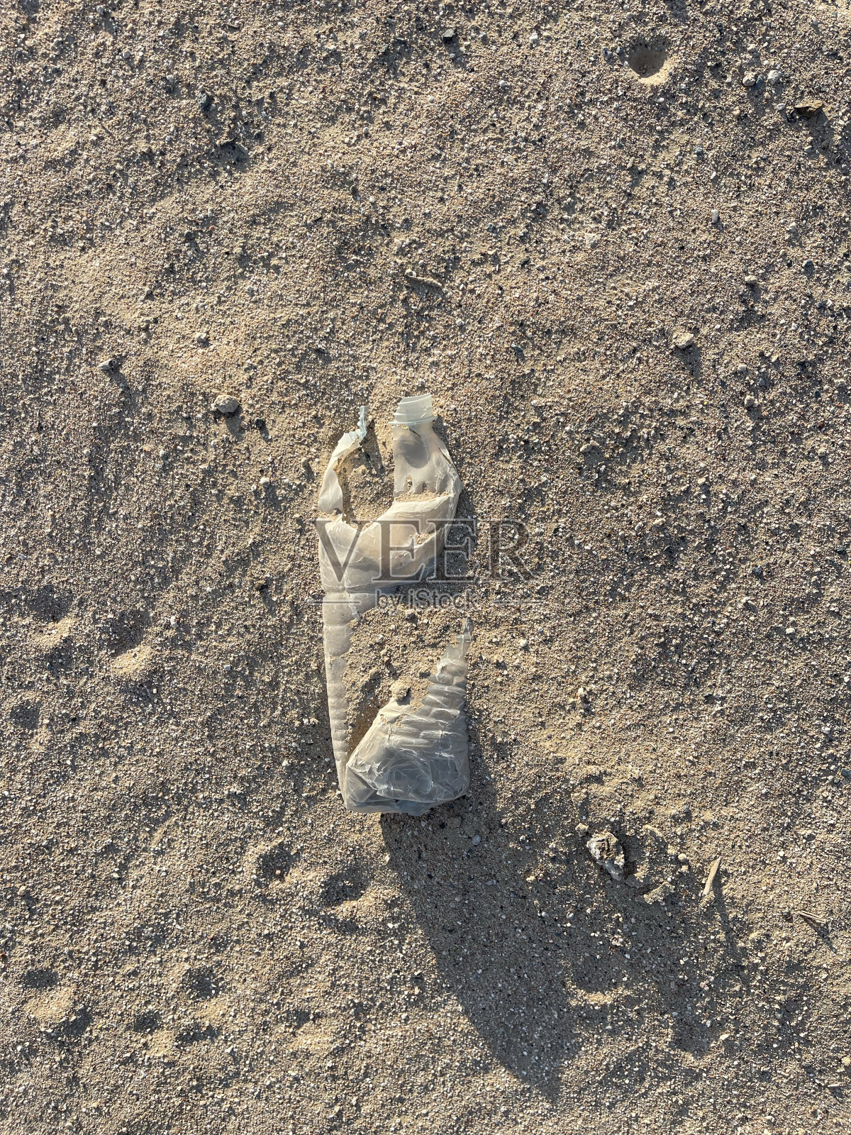 沙子里的塑料瓶象征着环境问题照片摄影图片