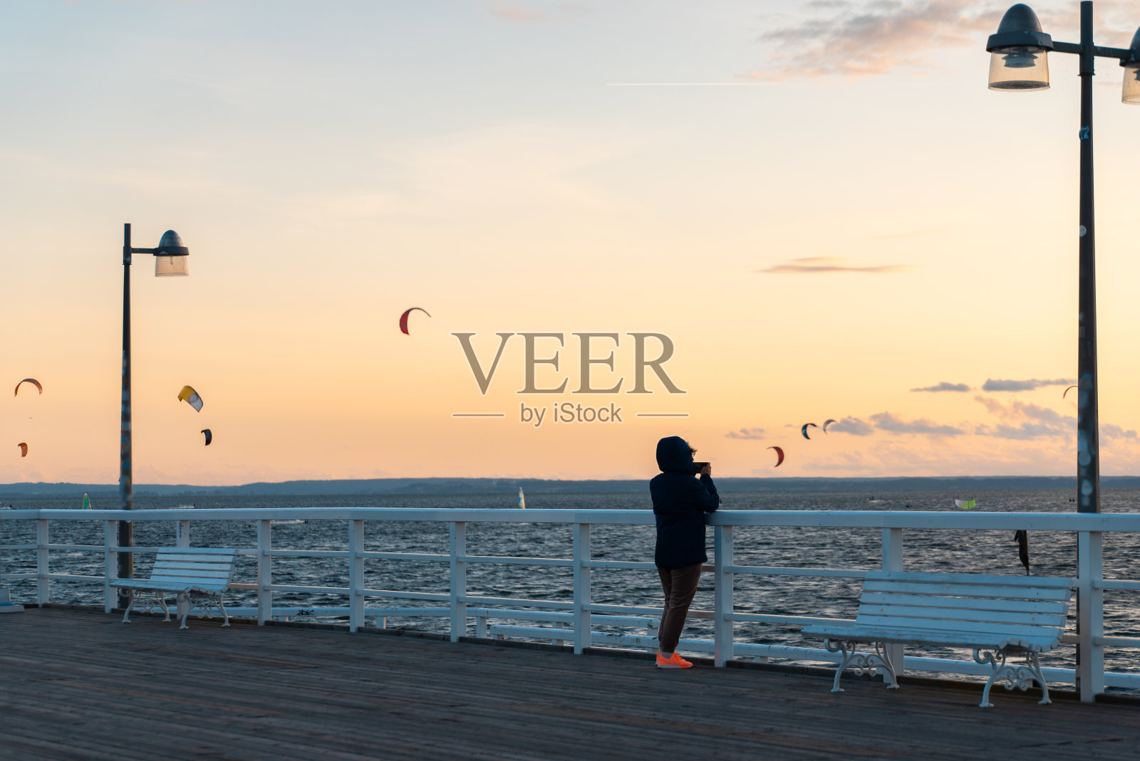 孤独的女人在秋海的木码头，人们在海滨小镇放松照片摄影图片